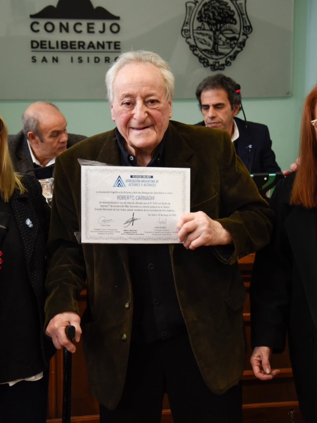 El reconocido actor Roberto Carnaghi sonríe mientras recibe un certificado de homenaje por su destacada trayectoria artística y cultural en el Concejo Deliberante de San Isidro. (Crédito: @oricuello)