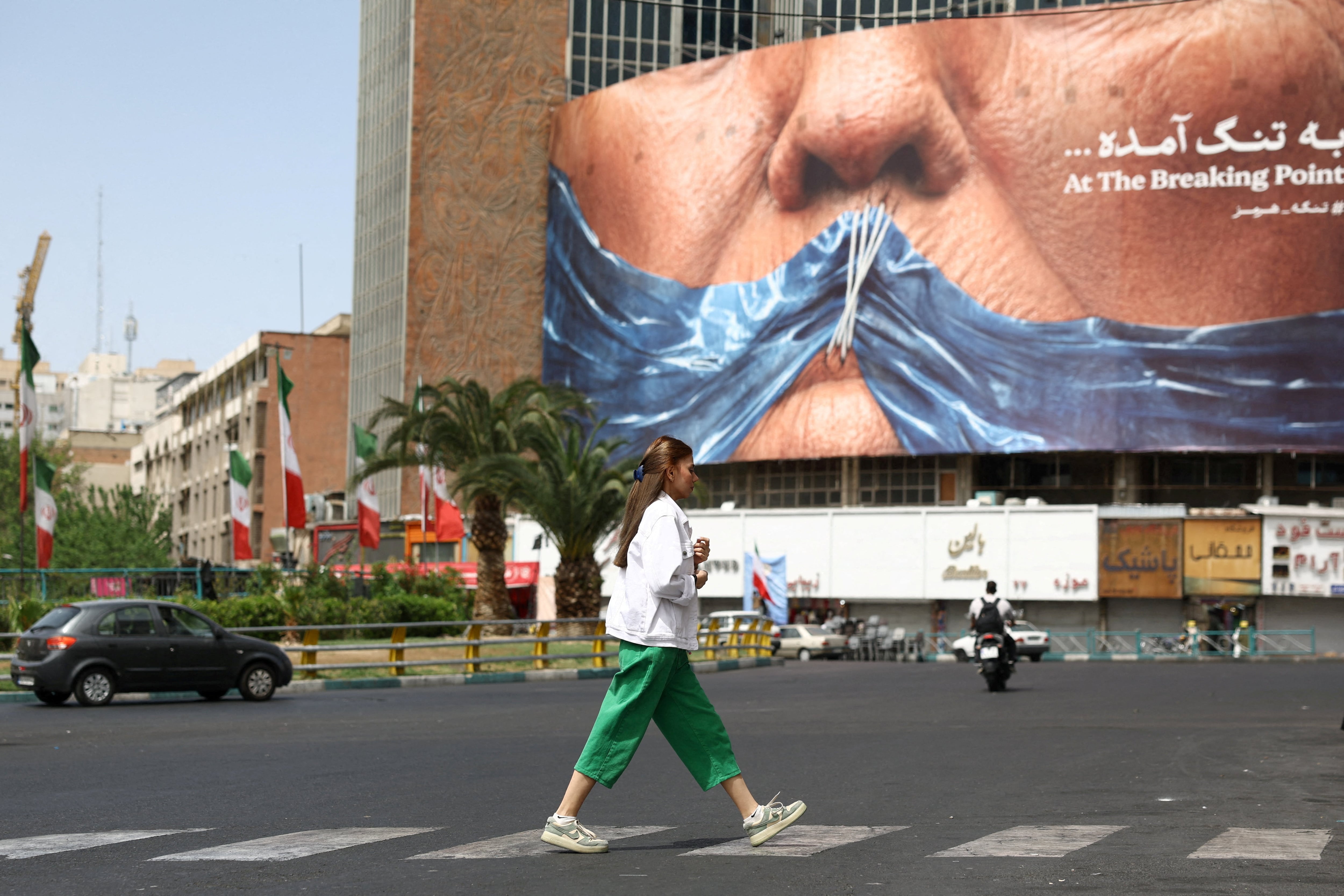 Una mujer pasa junto a una valla publicitaria contra Estados Unidos que representa al presidente estadounidense Donald Trump y el estrecho de Ormuz, en Teherán, Irán (REUTERS)