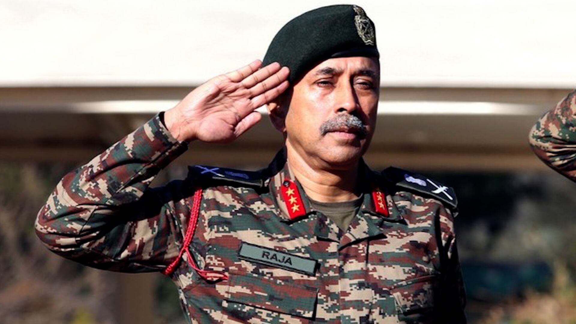 El oficial Raja Subramani, vestido con uniforme militar de camuflaje y boina, saluda mostrando respeto en un evento oficial