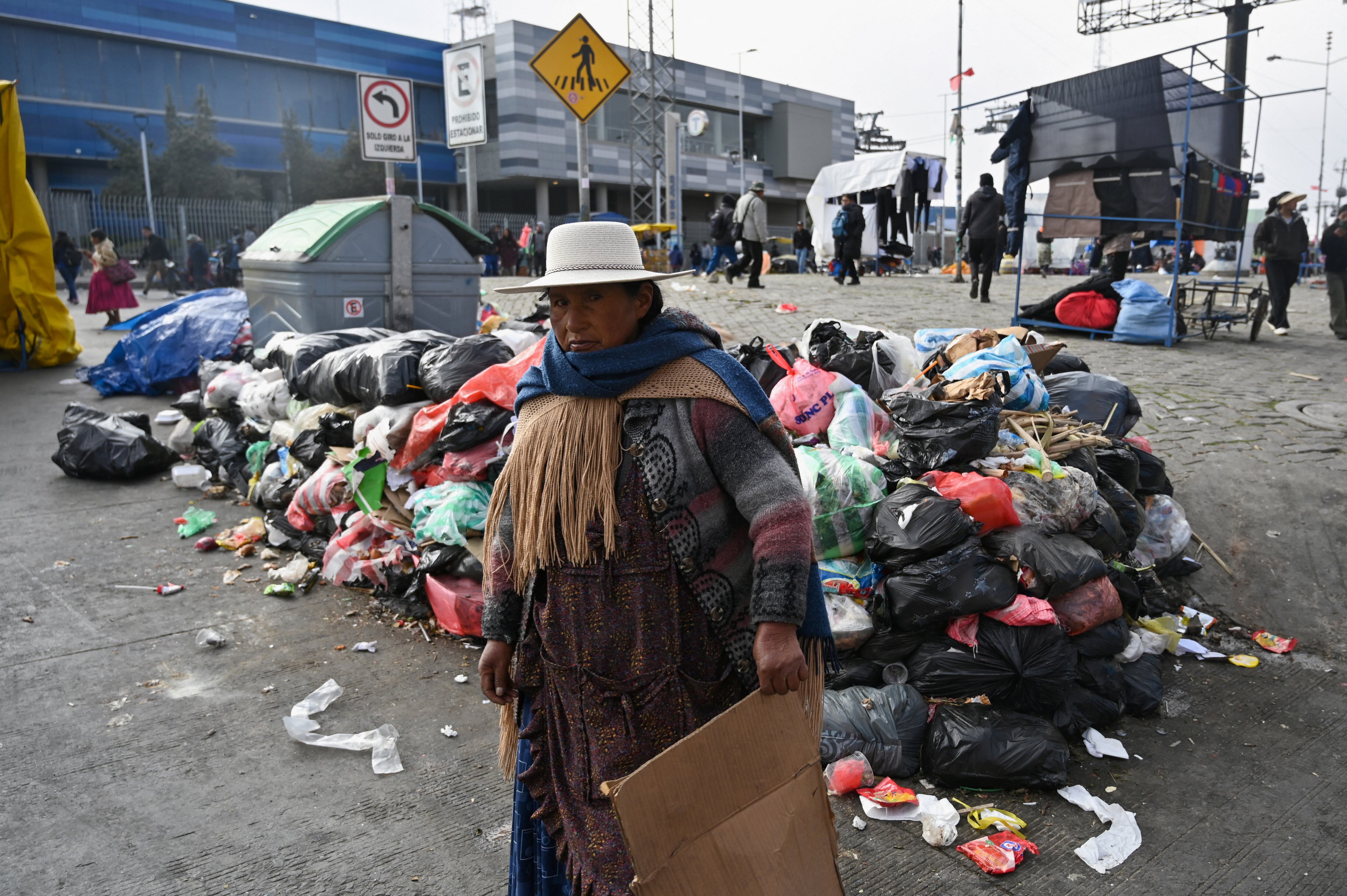 Una persona camina junto a montones de basura acumulados debido a los bloqueos y protestas que exigen la renuncia del presidente de Bolivia, Rodrigo Paz, mientras la crisis económica y energética del país se agrava (REUTERS/Claudia Morales)