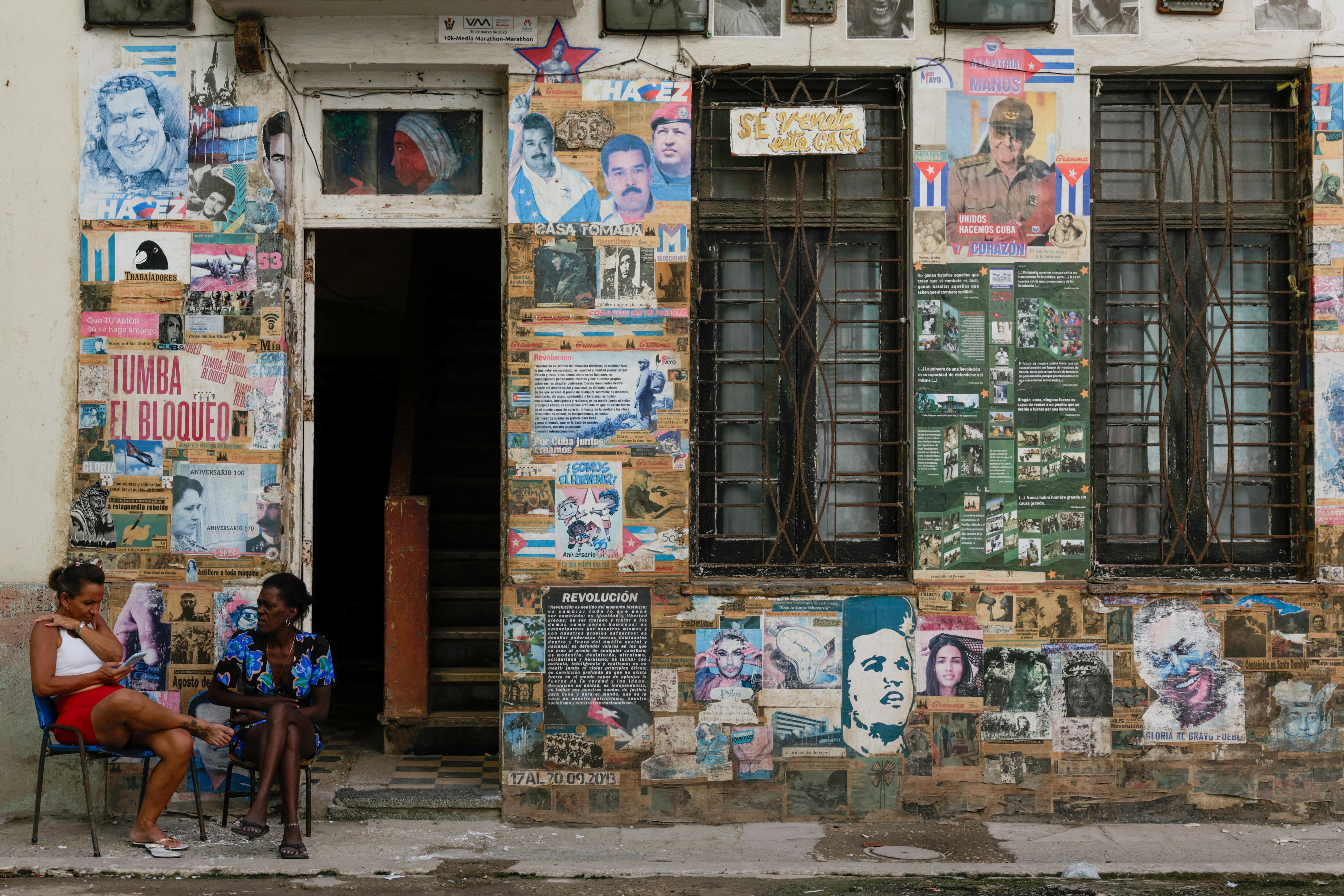 Mujeres sentadas cerca de un cartel del ex presidente cubano Raúl Castro, que ha sido acusado en Estados Unidos en una medida que marca una escalada en la campaña de presión de Washington contra el gobierno comunista de la isla caribeña, La Habana, Cuba, 20 de mayo de 2026. REUTERS/Norlys Perez