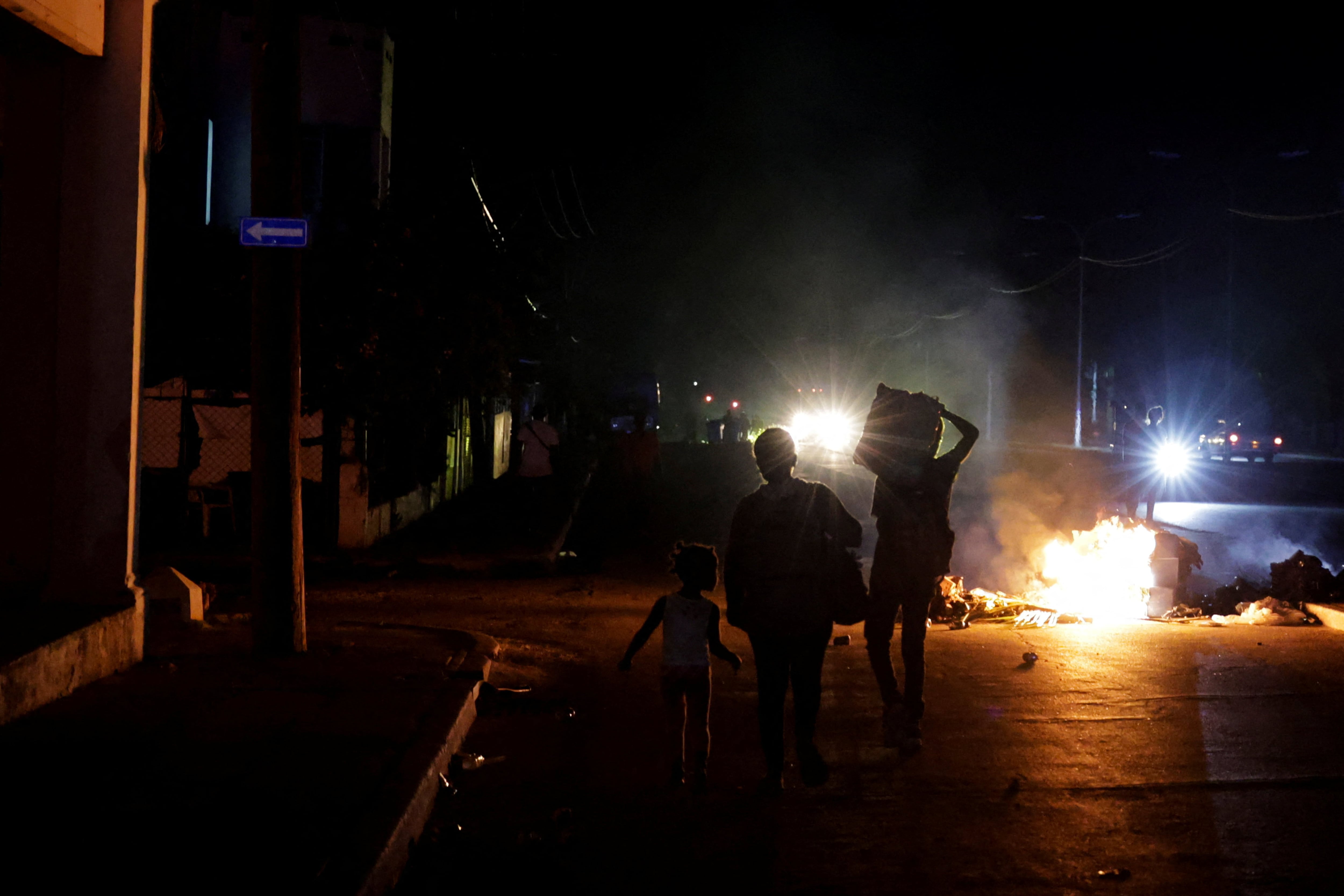 Un grupo de personas pasa junto a la basura prendida fuego en medio de una calle durante una protesta contra los frecuentes cortes de electricidad, en La Habana (REUTERS/Norlys Pérez)