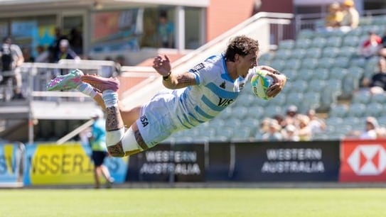Luciano González se lanza acrobáticamente para anotar un try crucial durante el torneo SVNS, exhibiendo la destreza del equipo argentino en el rugby sevens.