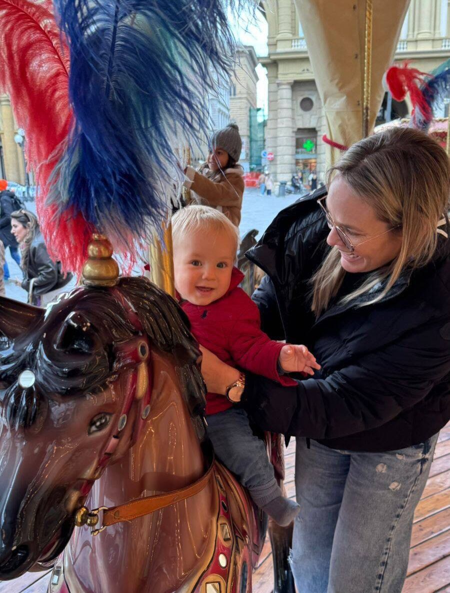 Muni junto al pequeño, quien se divierte sentado arriba de un caballo durante una calesita