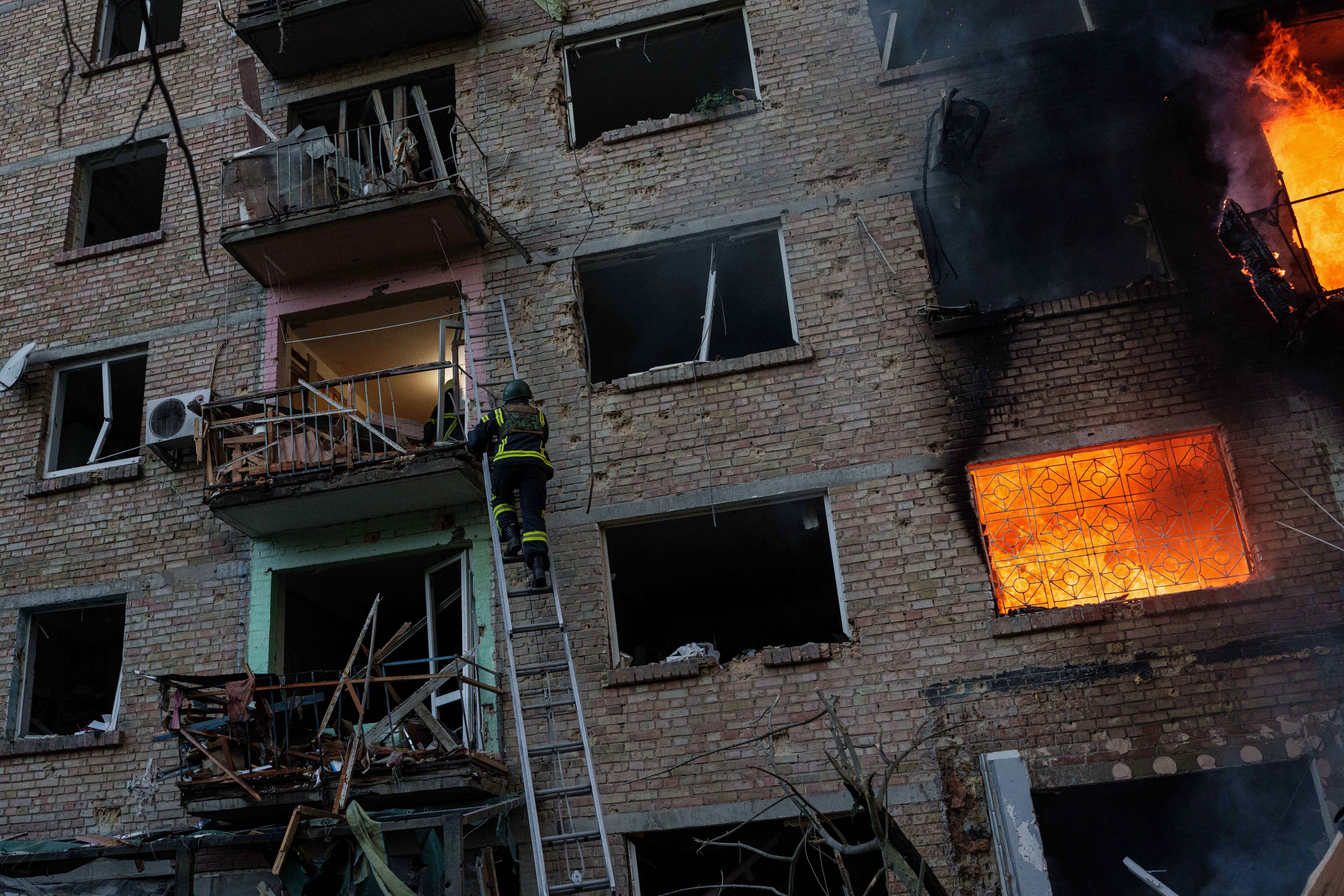 Un rescatista sube por una escalera para evacuar a vecinos de un edificio residencial destruido por el bombardeo ruso del domingo sobre Kiev, que mató al menos a cuatro personas en la capital y su región. (AP Photo/Evgeniy Maloletka)