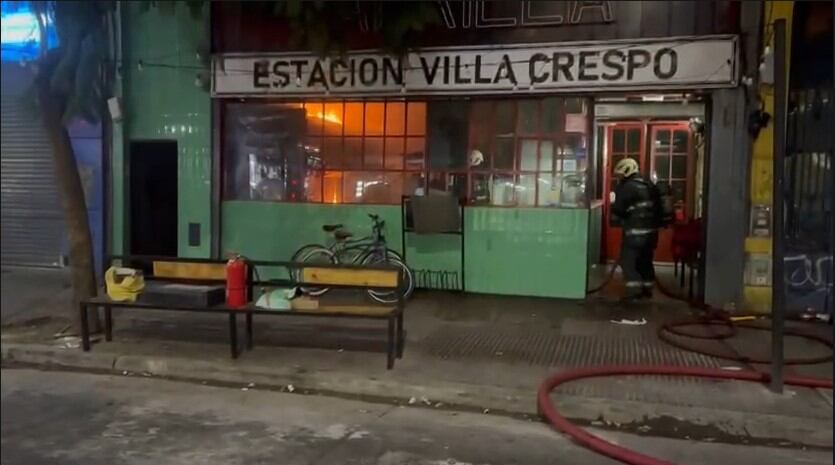 Un bombero trabaja en la extinción de un intenso incendio visible a través de los escaparates de un local en Villa Crespo.