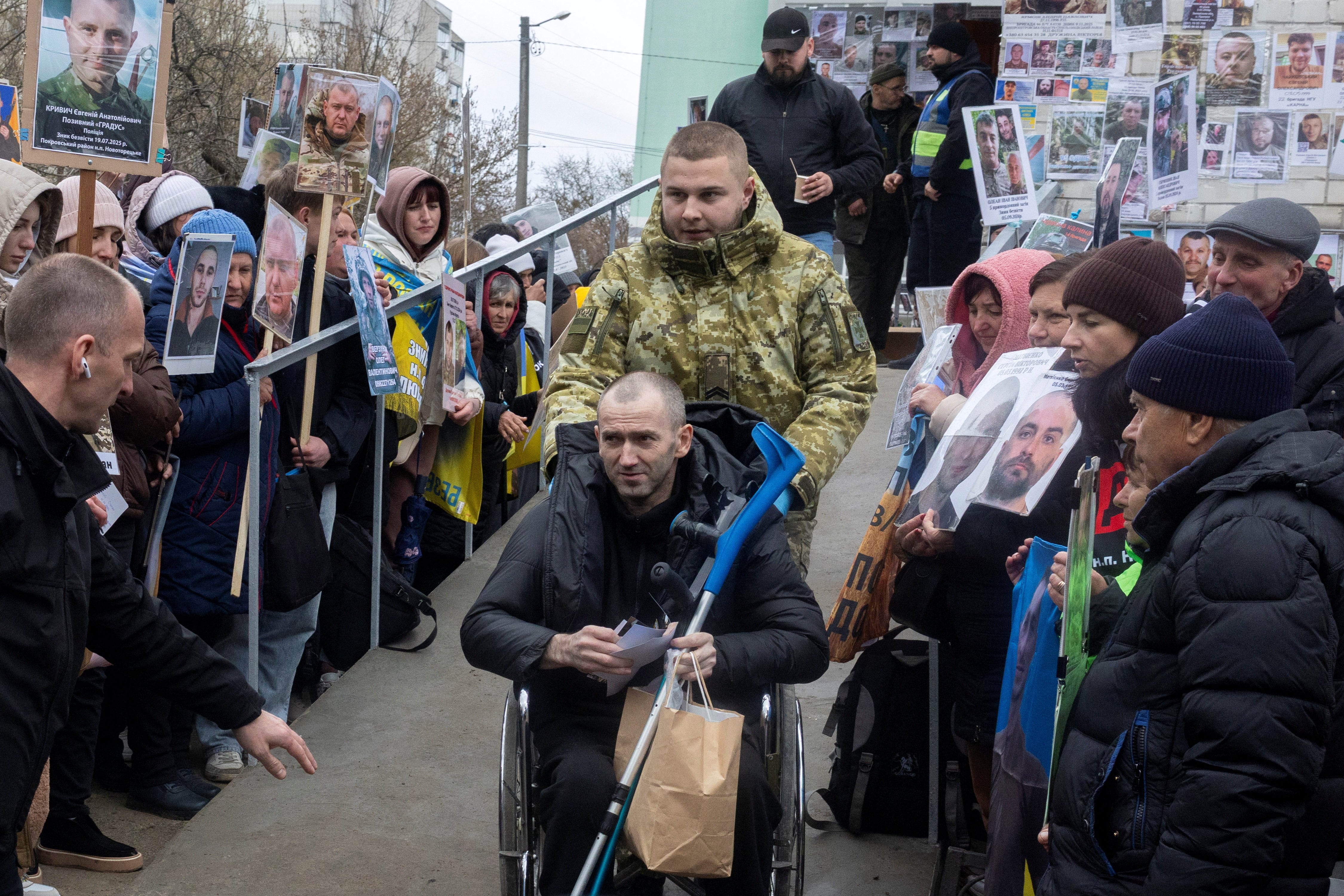 Un prisionero de guerra ucraniano está rodeado de personas que sostienen fotografías de soldados ucranianos desaparecidos a su regreso tras un intercambio de prisioneros, el 11 de abril de 2026 (REUTERS/Thomas Peter)