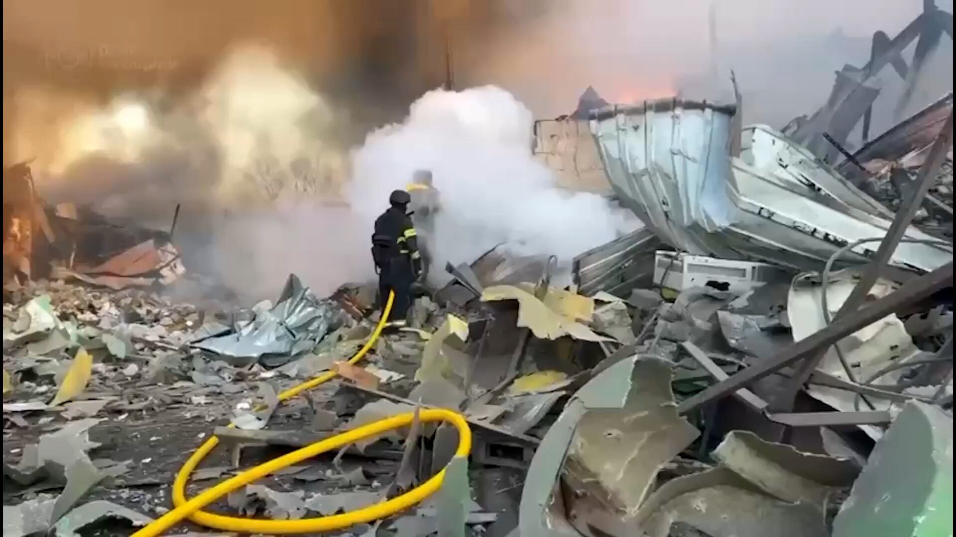 Bomberos ucranianos trabajan entre los escombros y el humo de un edificio destruido tras el masivo ataque ruso denunciado por Volodimir Zelensky contra Ucrania. (Captura de video)