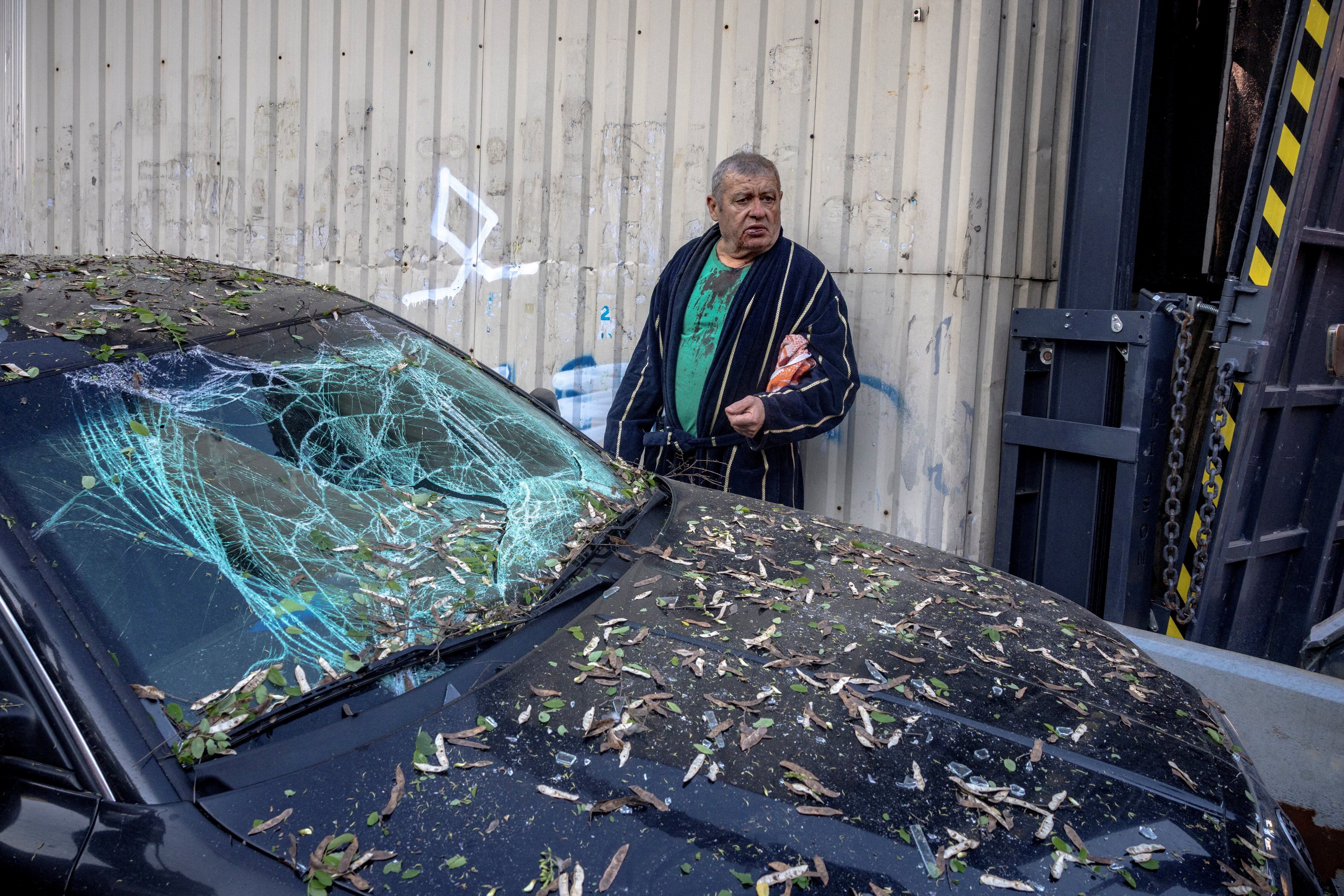 Serhii, un residente herido por la metralla, permanece junto a su automóvil destruido frente a un edificio parcialmente derrumbado tras los ataques rusos sobre Kiev (REUTERS/Thomas Peter)