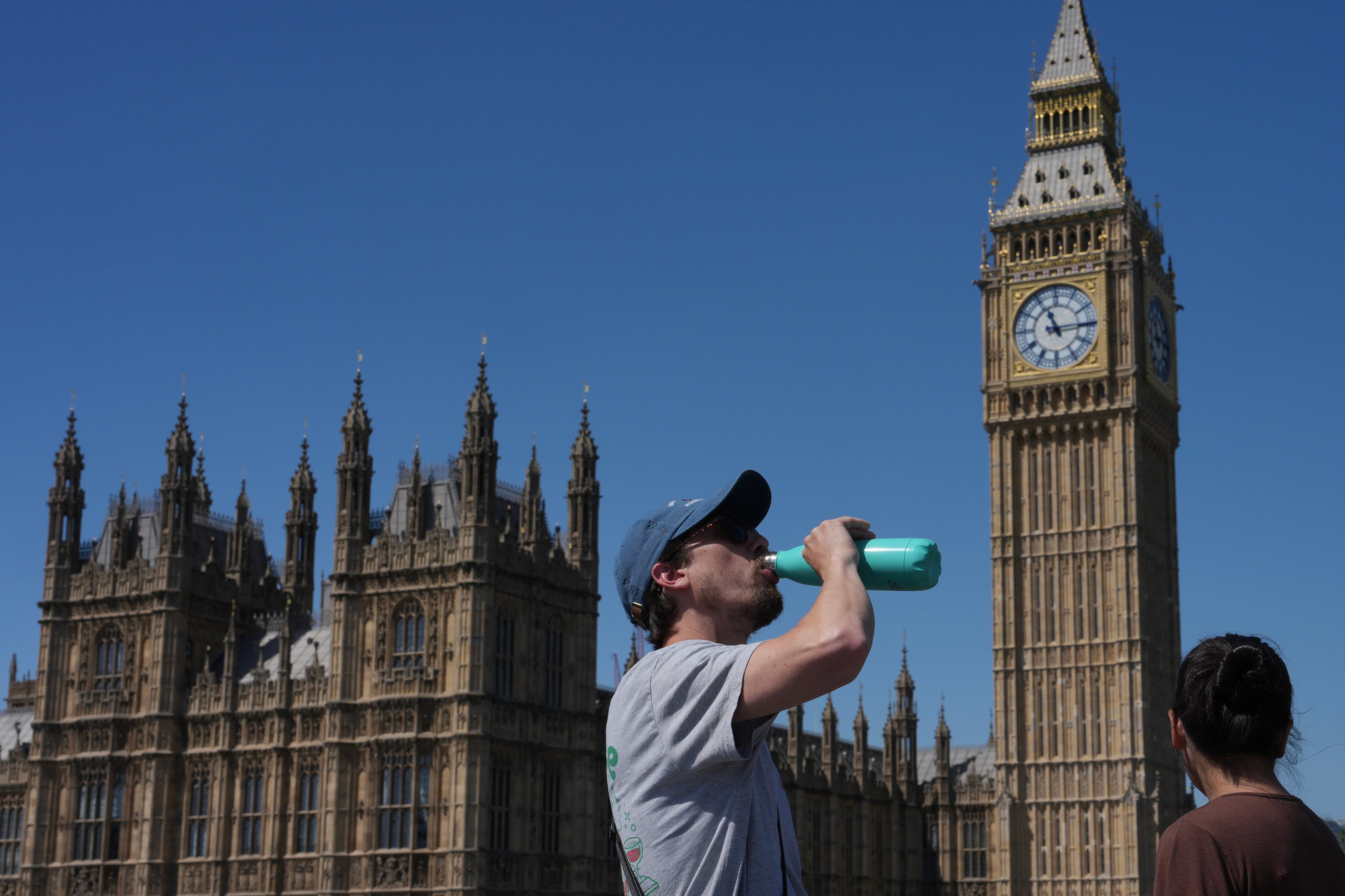 Un hombre se hidrata frente al Palacio de Westminster, sede del Parlamento británico, durante la jornada en que Londres registró su temperatura más alta en un mes de mayo desde que hay registros. (AP Photo/Kin Cheung)