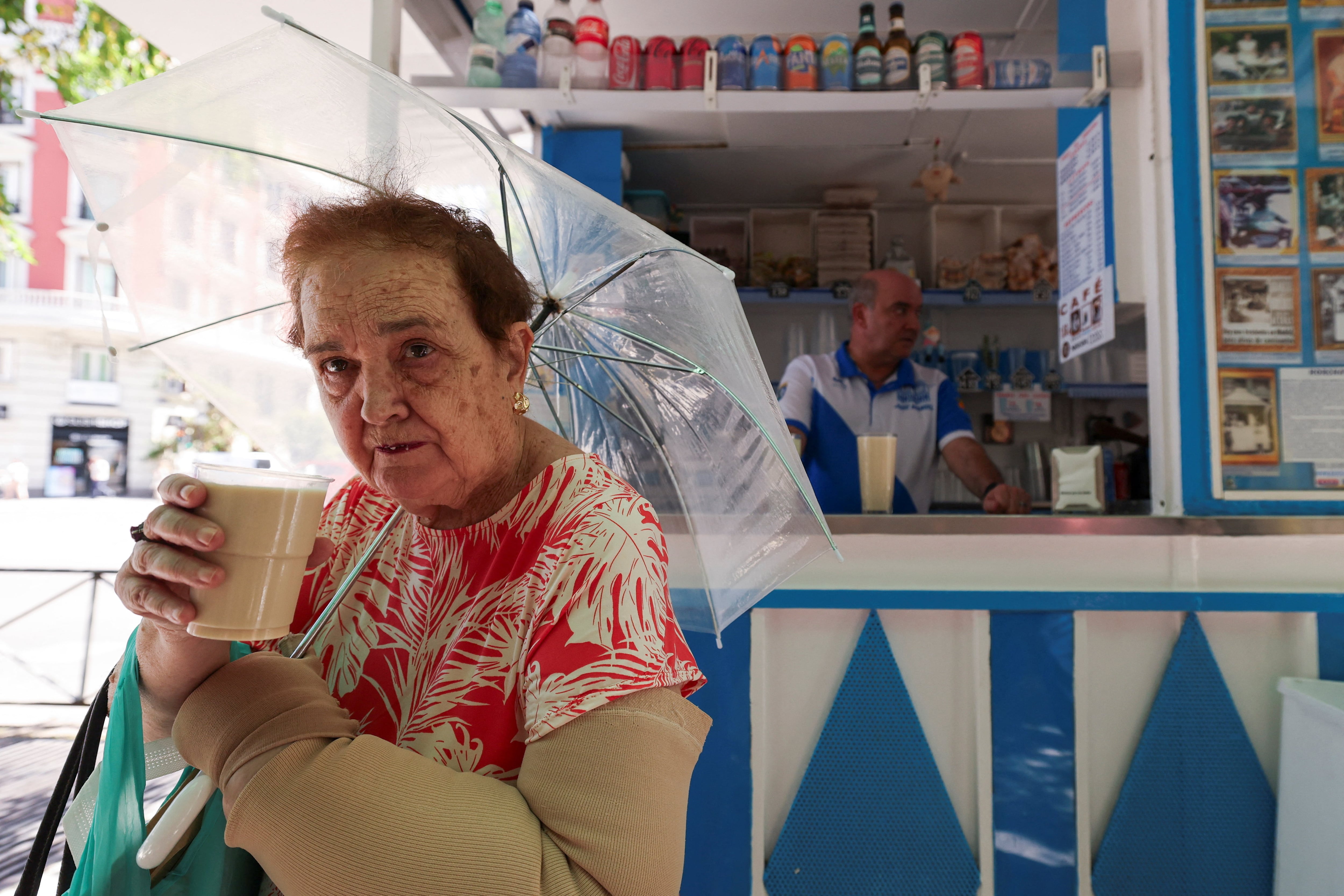 Una madrileña sostiene un vaso de horchata en el último quiosco tradicional de bebidas de Madrid, refugio de locales y turistas durante la ola de calor que llevó los termómetros a rozar los 40 °C en la península ibérica. (REUTERS/Violeta Santos Moura)