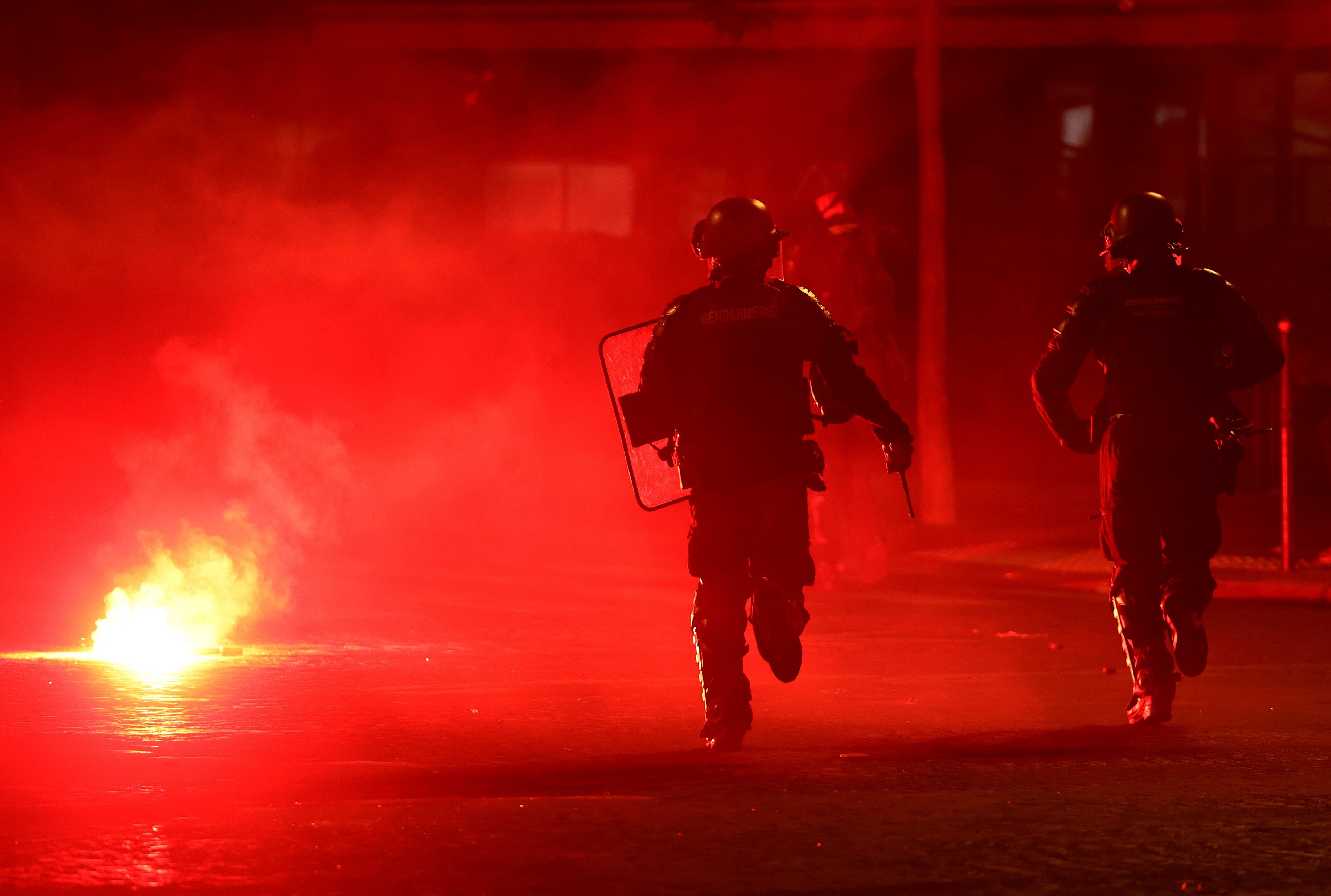 Fútbol - Liga de Campeones de la UEFA - Aficionados del Paris Saint-Germain celebran la victoria en la Liga de Campeones de la UEFA - París, Francia - 31 de mayo de 2026. Agentes de policía se protegen de una bengala tras la victoria del Paris Saint-Germain en la Liga de Campeones de la UEFA. REUTERS/Abdul Saboor