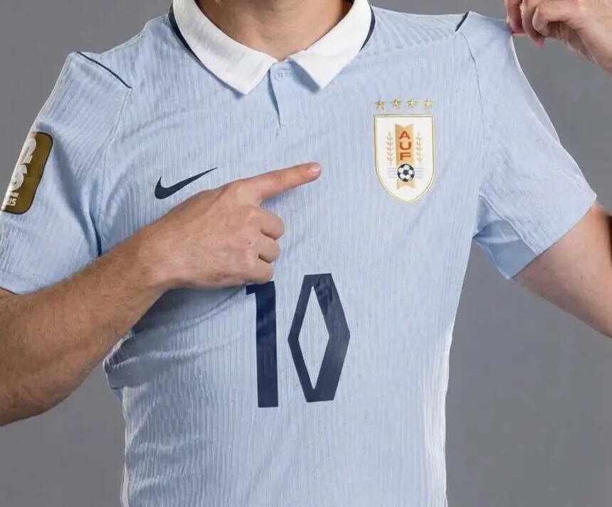 El color celeste, adoptado por Uruguay en 1910, es uno de los símbolos más reconocibles del fútbol mundial; la nueva camiseta incorpora una tipografía inspirada en el diseño Art Déco de la época del Mundial de 1930, mientras las cuatro estrellas sobre el escudo evocan las conquistas de 1924, 1928, 1930 y 1950, que hicieron de la Celeste una leyenda (Recreación digital Gemini) 