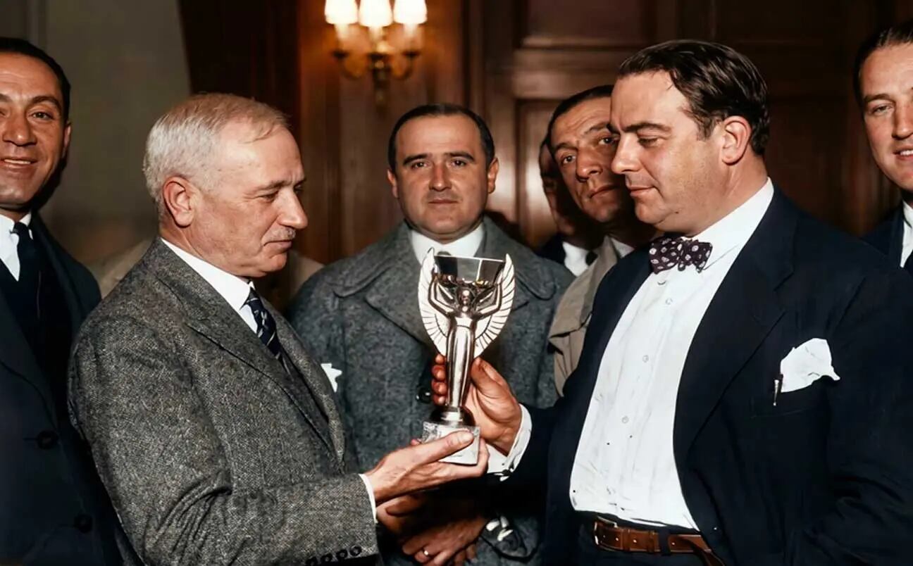 Entrega de la Copa del Mundo (1930): la joya cincelada por el artífice galo Abel Lafleur y llegada bajo la celosa custodia de Monsieur Jules Rimet, pasa a manos del presidente de la AUF, Dr. Raúl Jude, quien dentro de su esfera hizo tanto como el más brioso de los «centauros» de la camiseta color cielo (Fuente AUF) 