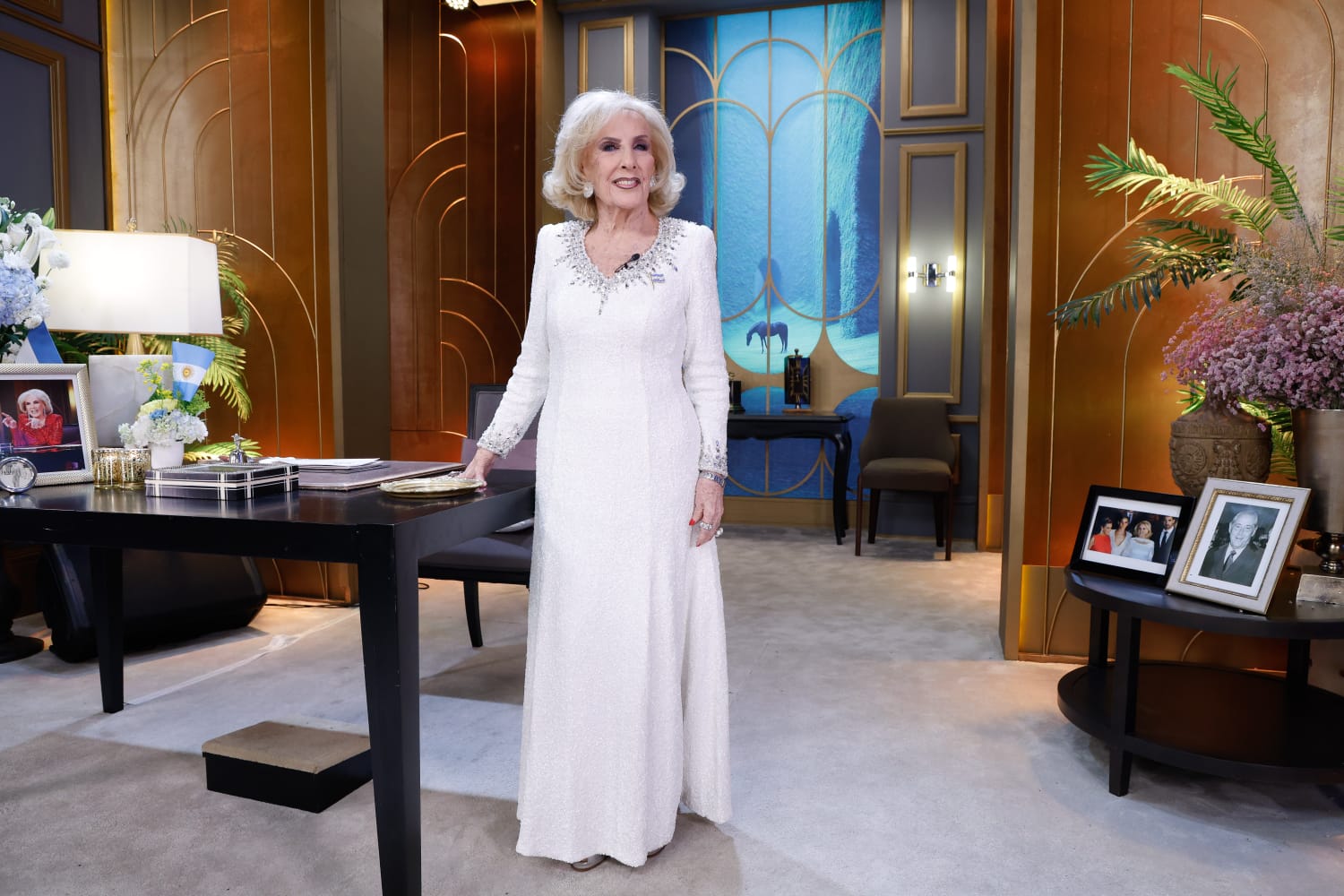 La presentadora Mirtha Legrand posa en el set de su programa de televisión luciendo un vestido blanco de gala.