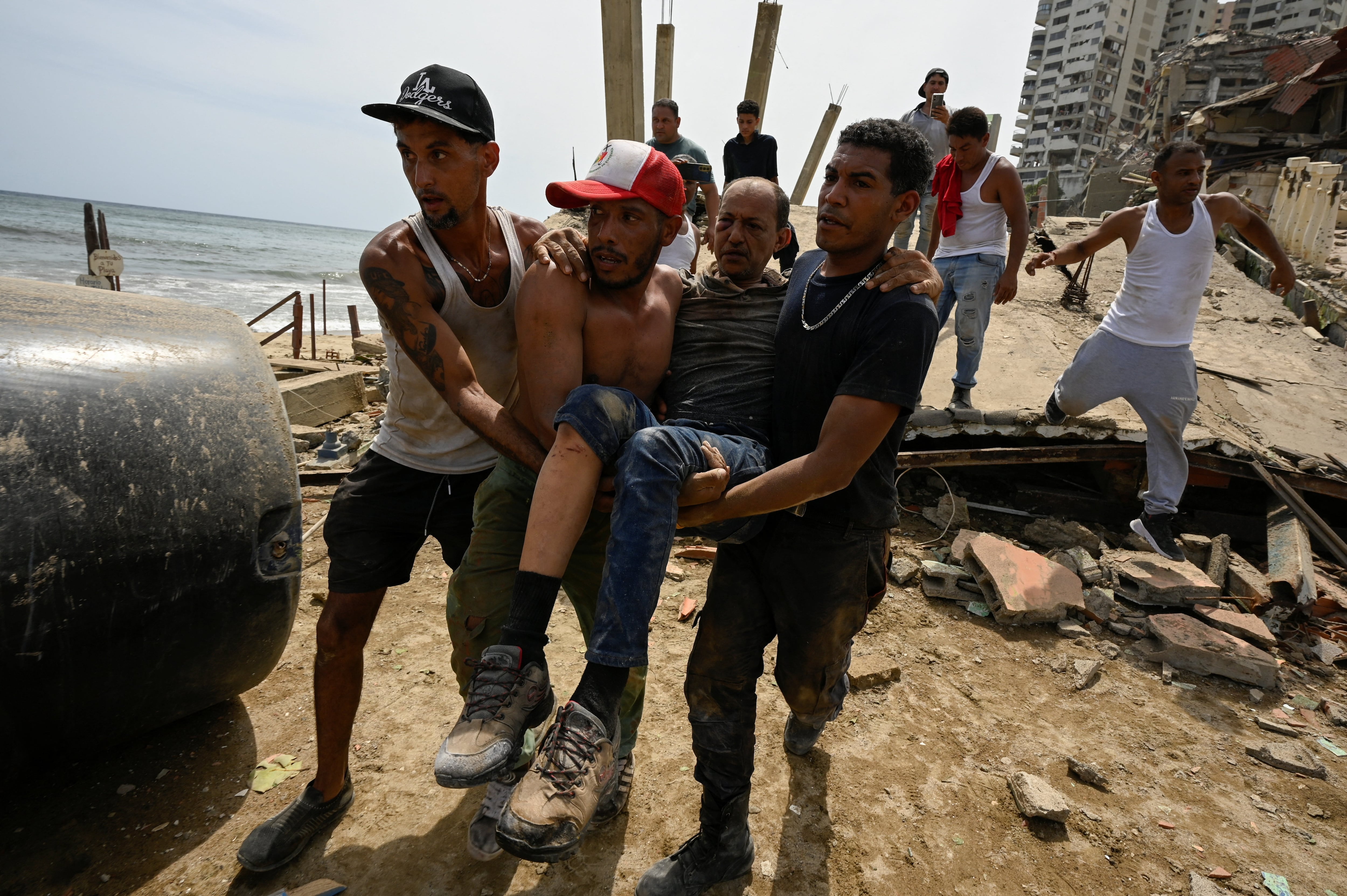 Rescatistas y vecinos trasladan a un hombre herido tras los terremotos que devastaron La Guaira, mientras continúan las labores de emergencia (REUTERS)