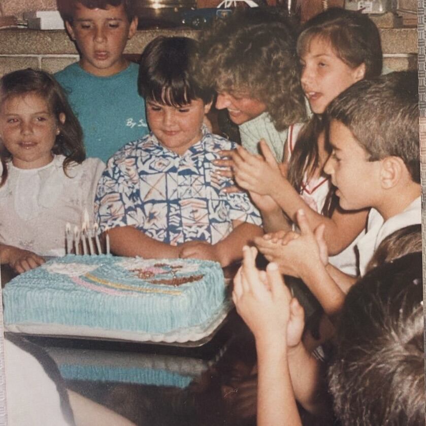 Darío Barassi, de niño, sonríe junto a su familia y amigos en una celebración de cumpleaños junto a su mamá e invitados