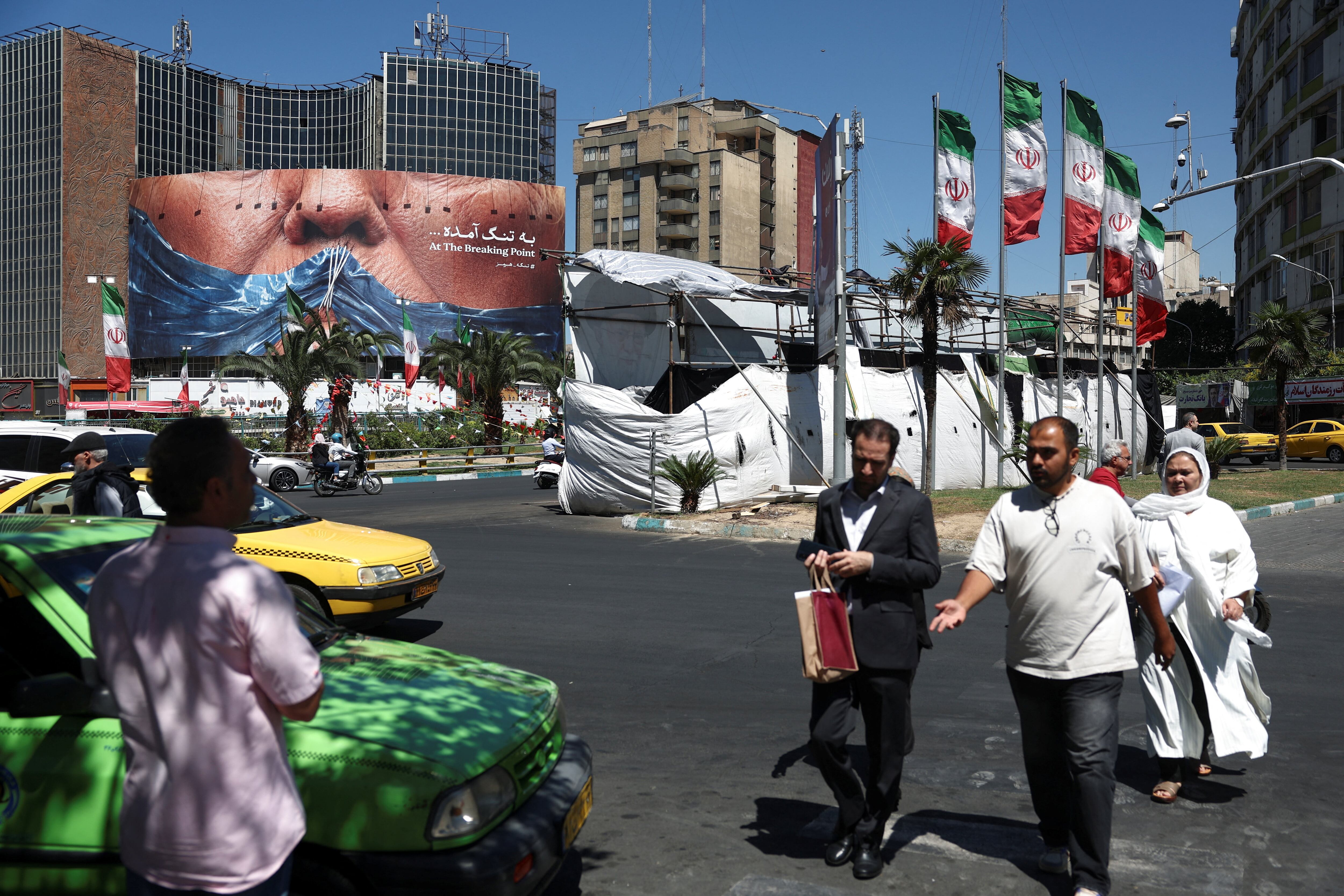 Varias personas pasan junto a una valla publicitaria antiestadounidense que representa al presidente de Estados Unidos, Donald Trump, y el estrecho de Ormuz, en Teherán, Irán, el 26 de mayo de 2026. Majid Asgaripour/WANA (Agencia de Noticias de Asia Occidental) vía REUTERS
