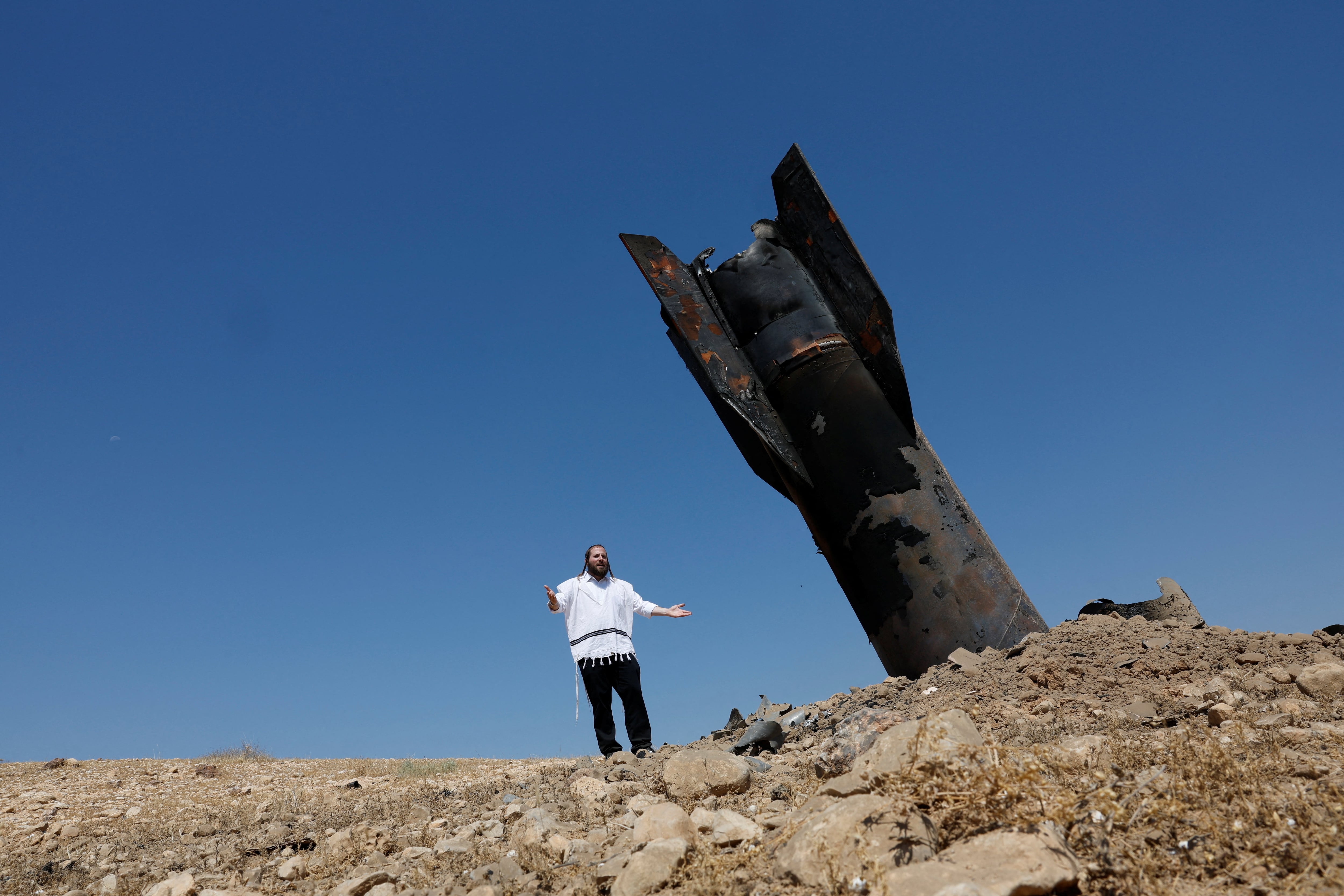 Una persona observa los restos de un misil iraní incrustado en el suelo en la Cisjordania, horas después de que Irán lanzara casi 30 proyectiles contra territorio israelí en represalia por los bombardeos sobre los suburbios de Beirut. (REUTERS/Ammar Awad)