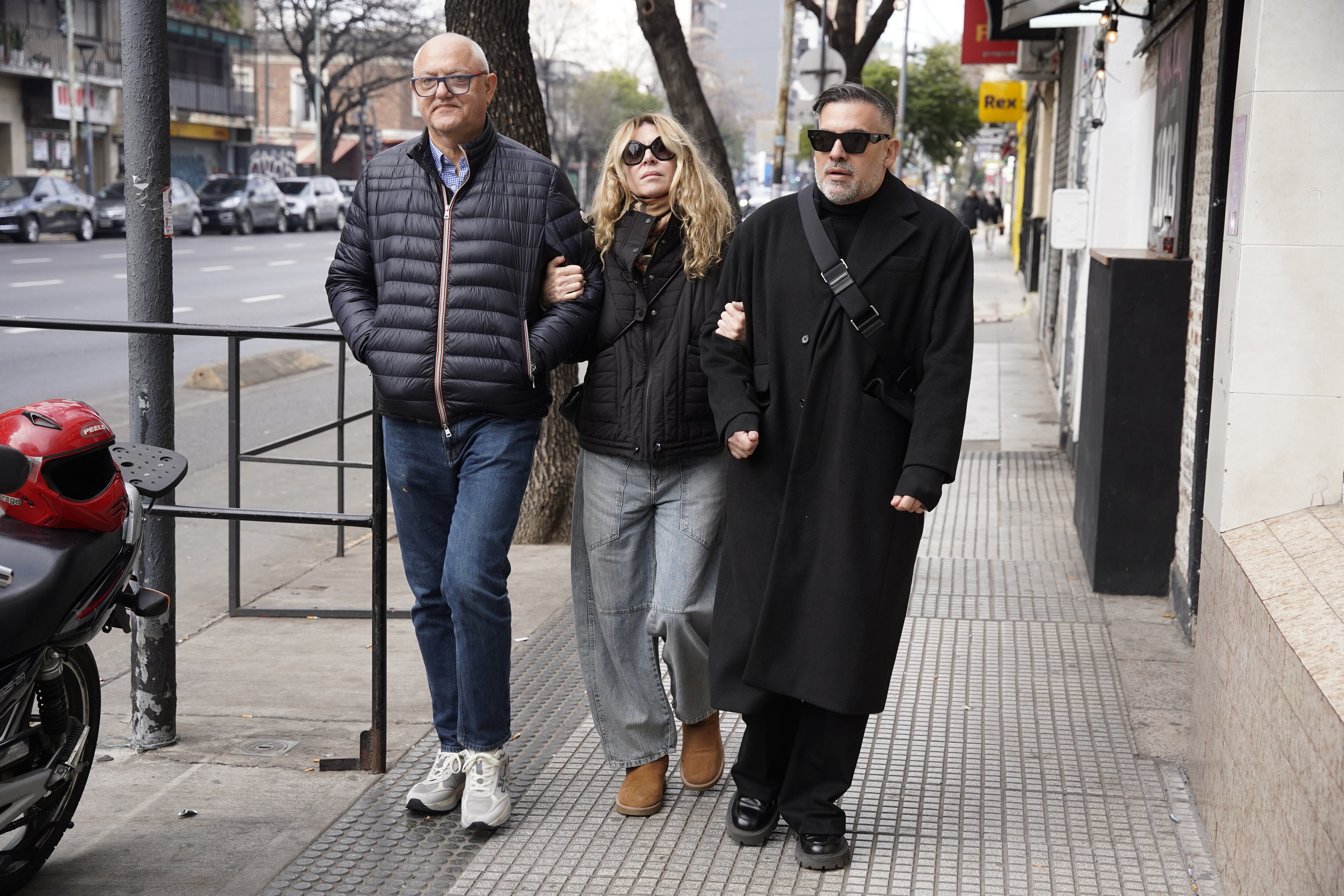 María Carámbula camina por una calle de la ciudad acompañada por dos hombres al llegar al velatorio de Ernestina Pais.