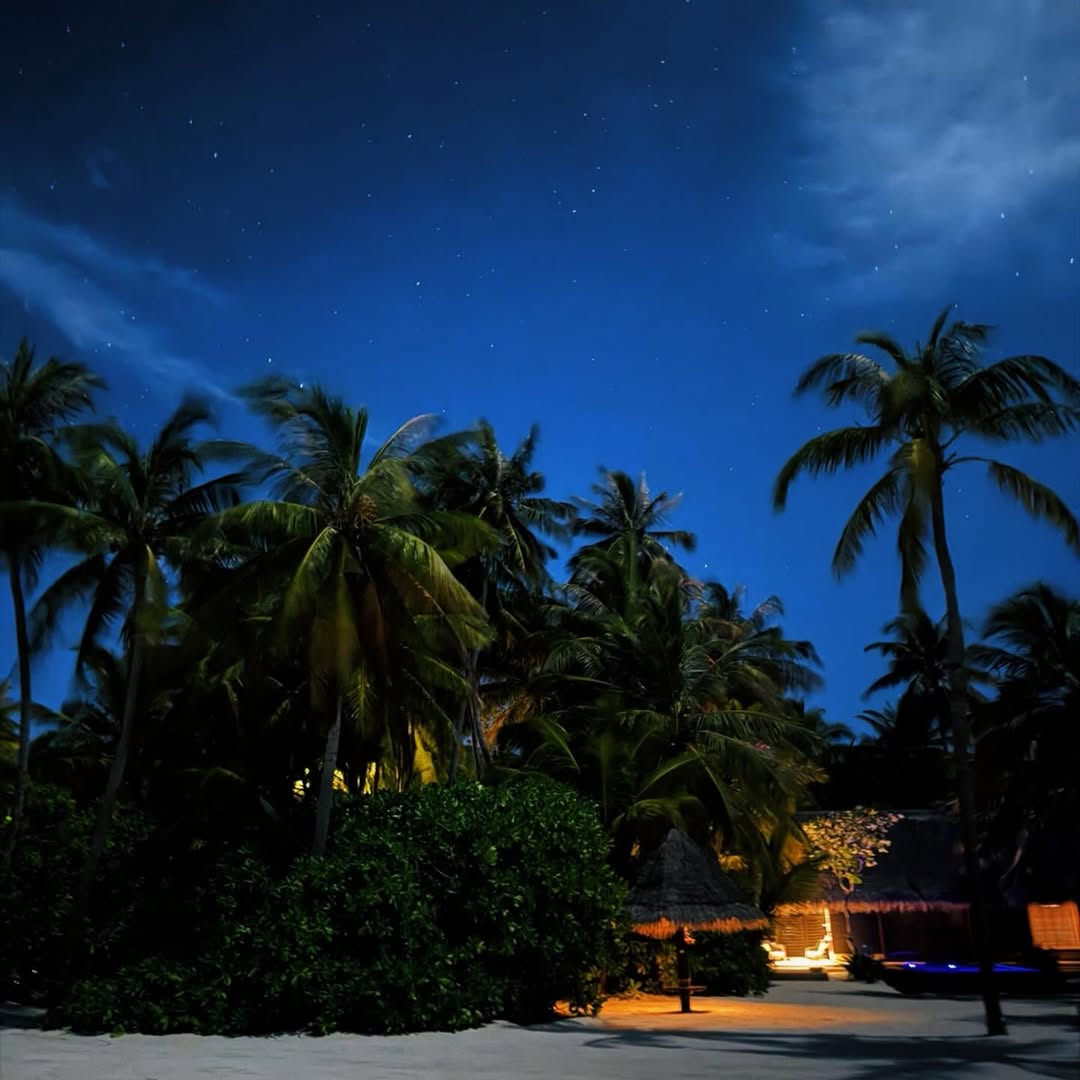 De noche, la playa iluminada por luces cálidas y un cielo estrellado mostró la atmósfera serena del complejo en las Islas Maldivas 
