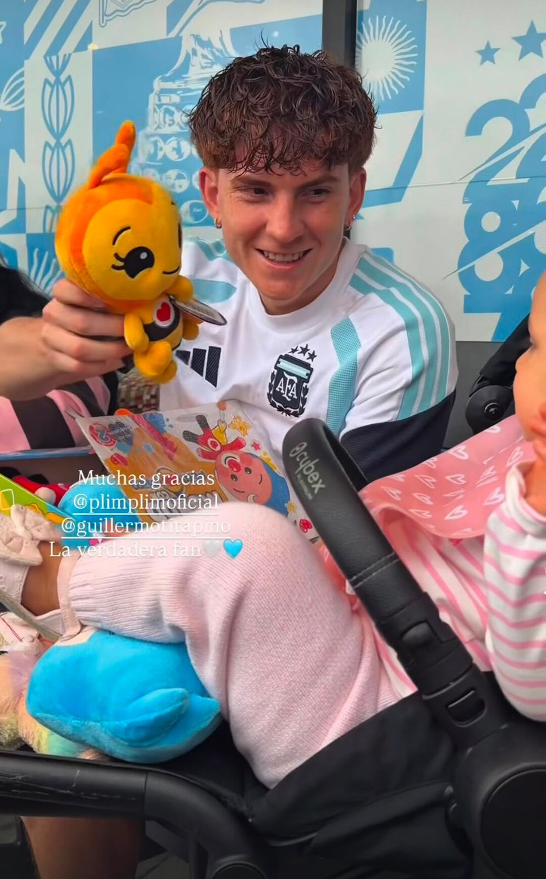 El futbolista argentino Colo Barco sonríe mientras muestra la Abejita Chiquitita a su hija Gemma, sentada en un cochecito en la concentración de la selección.