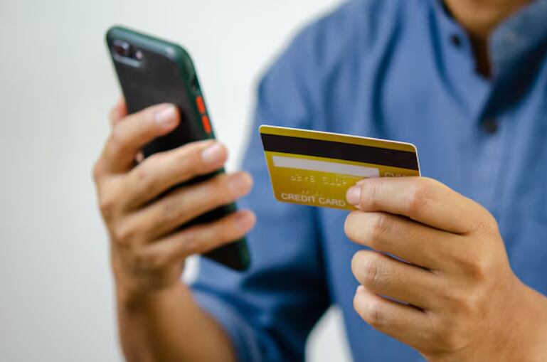 Una persona sostiene un teléfono móvil y una tarjeta de crédito, lista para realizar una compra o transacción en línea. (Freepik)