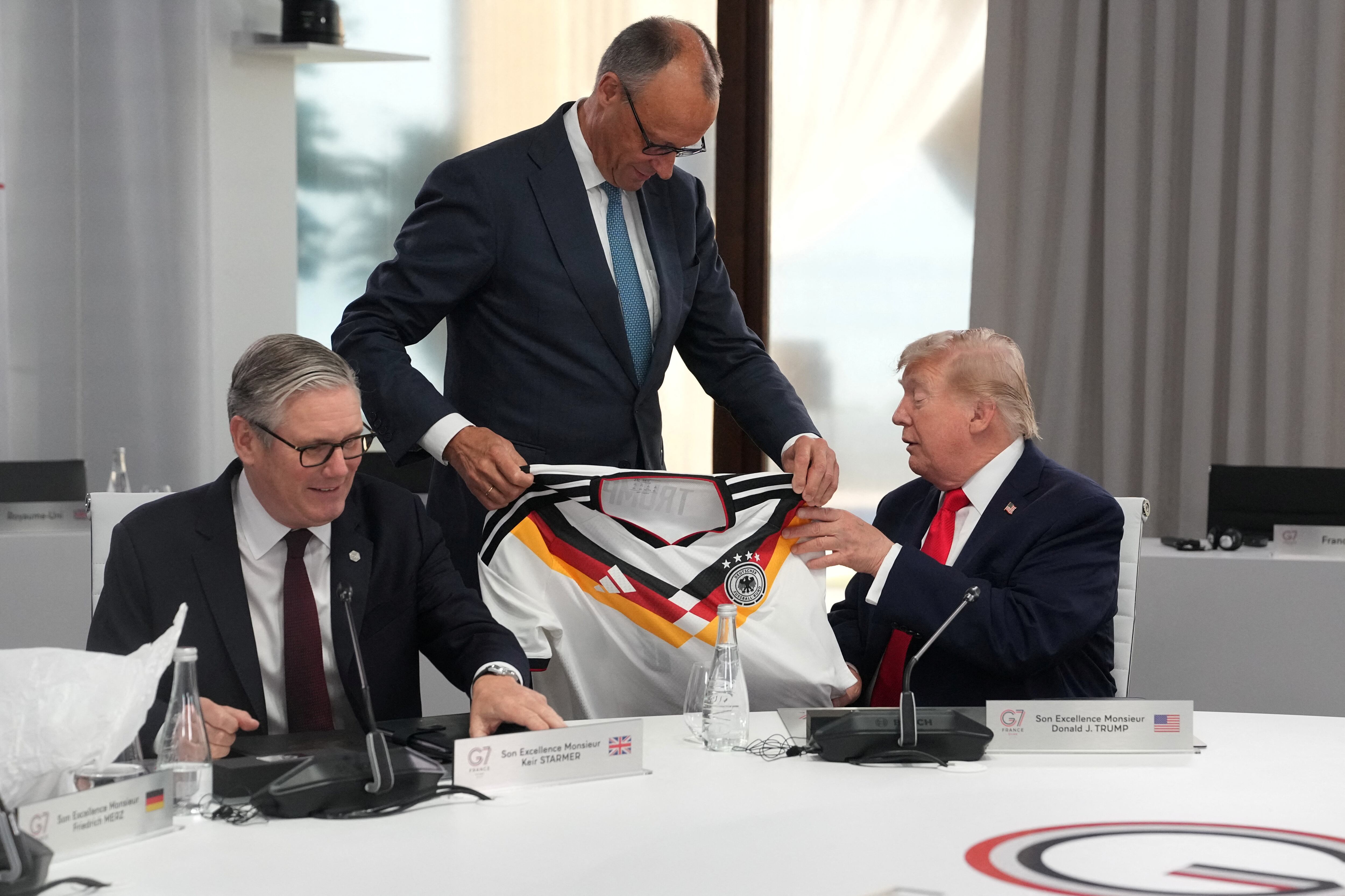 El canciller alemán Friedrich Merz entrega al presidente estadounidense Donald Trump una camiseta con el número 47, mientras el primer ministro británico Keir Starmer observa, durante una sesión de trabajo en la cumbre del G7 en Evian-les-Bains, Francia, el 16 de junio de 2026. Thibault Camus/Pool vía REUTERS