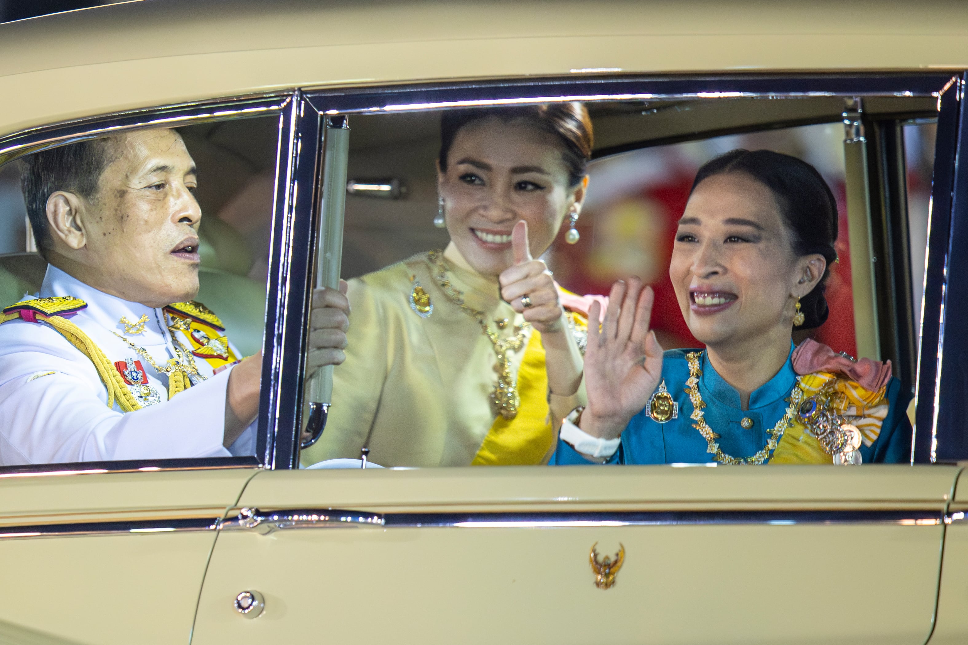 El rey tailandés Maha Vajiralongkorn, a la izquierda, la reina Suthida y la princesa Bajrakitiyabha Mahido saludan a sus seguidores en Bangkok, Tailandia, el 5 de mayo de 2020 (AP/Wason Wanichakorn)