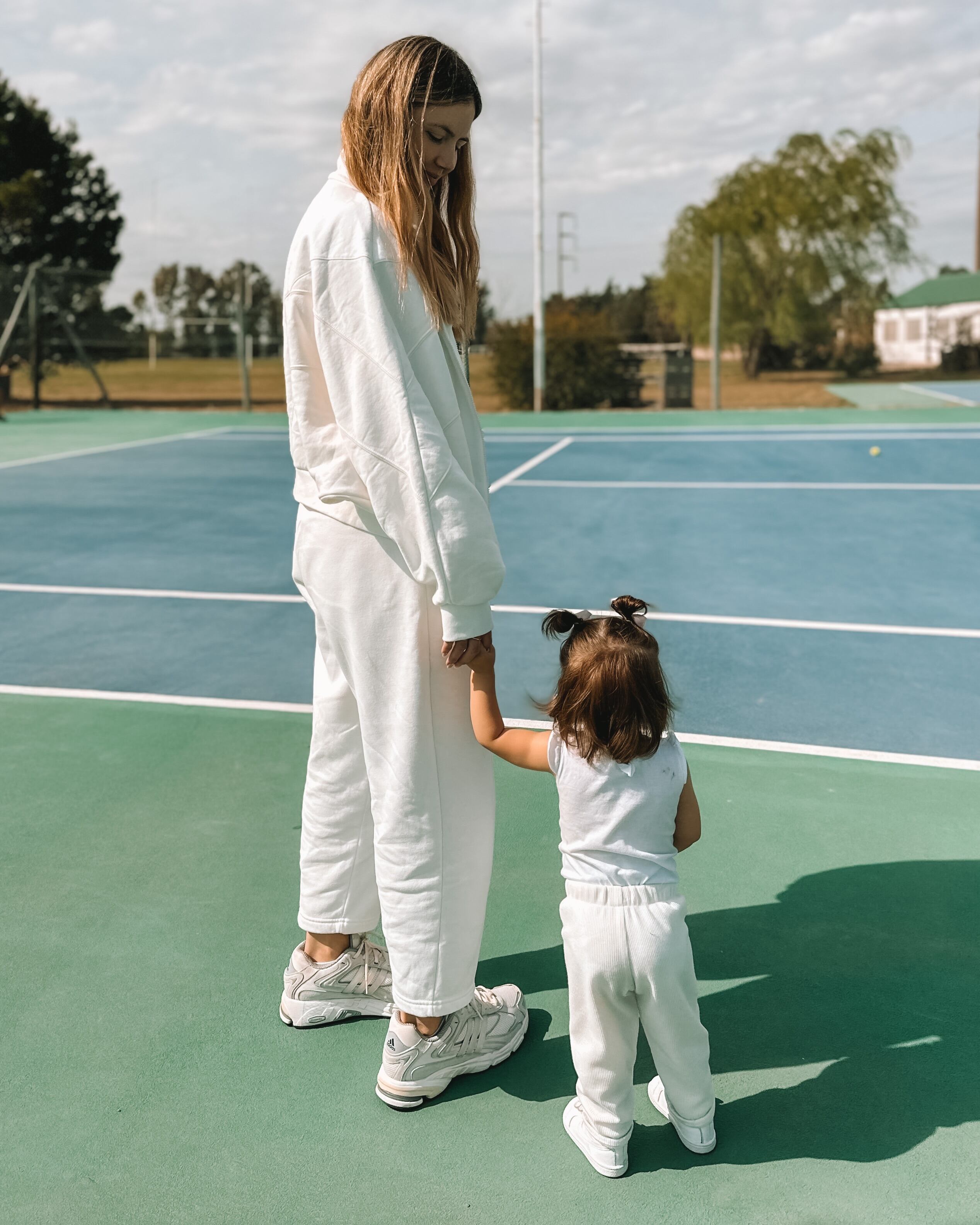 Demner y su hija Ariana tomadas de la mano en una cancha de tenis
