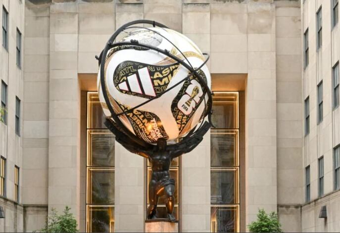 Una estatua exhibe una réplica del balón Adidas Trionda Final del Mundial 2026 en un contexto urbano, con edificios de fondo.