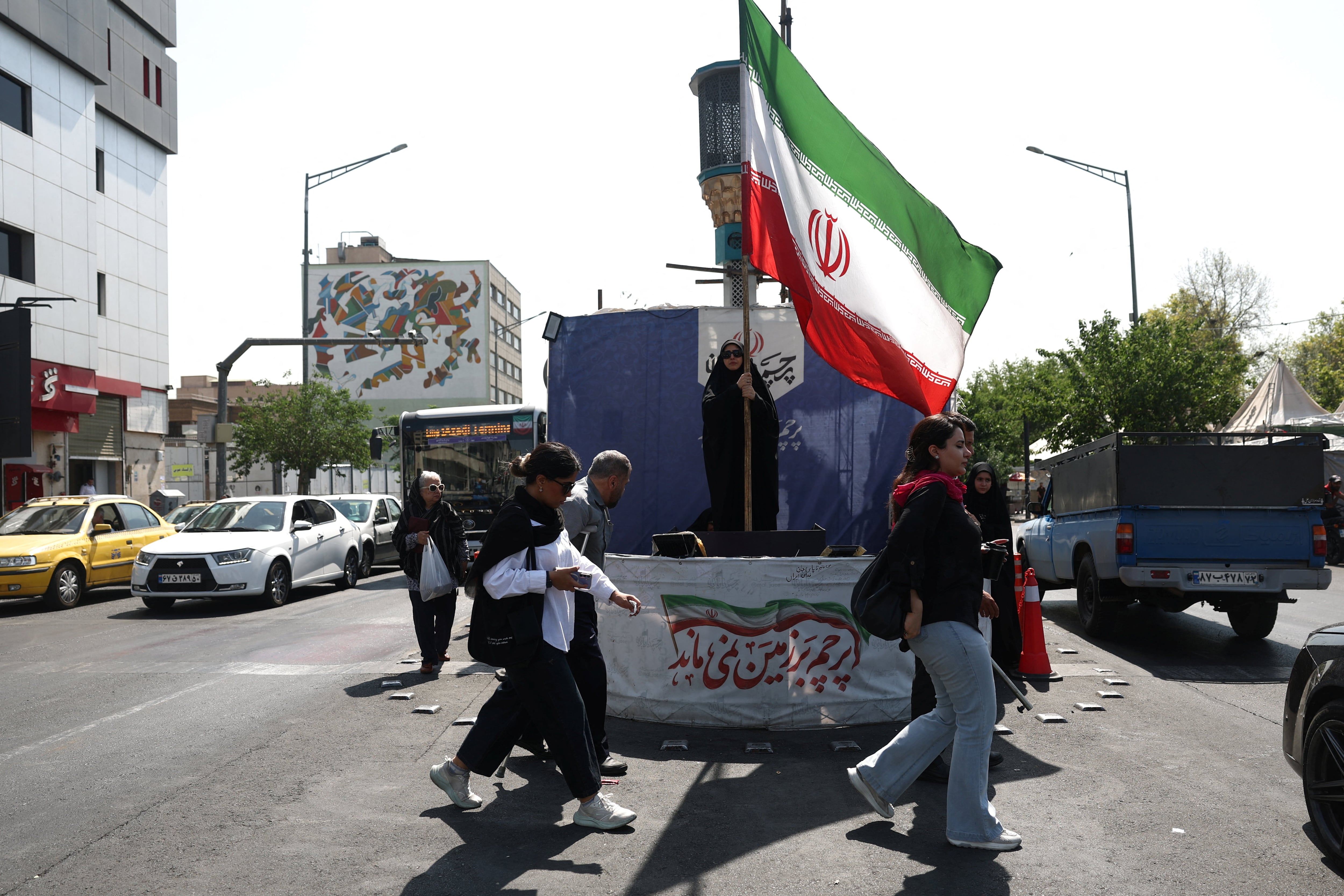 Una mujer sostiene una bandera iraní en una calle de Teherán, Irán (Majid Asgaripour/WANA vía REUTERS)