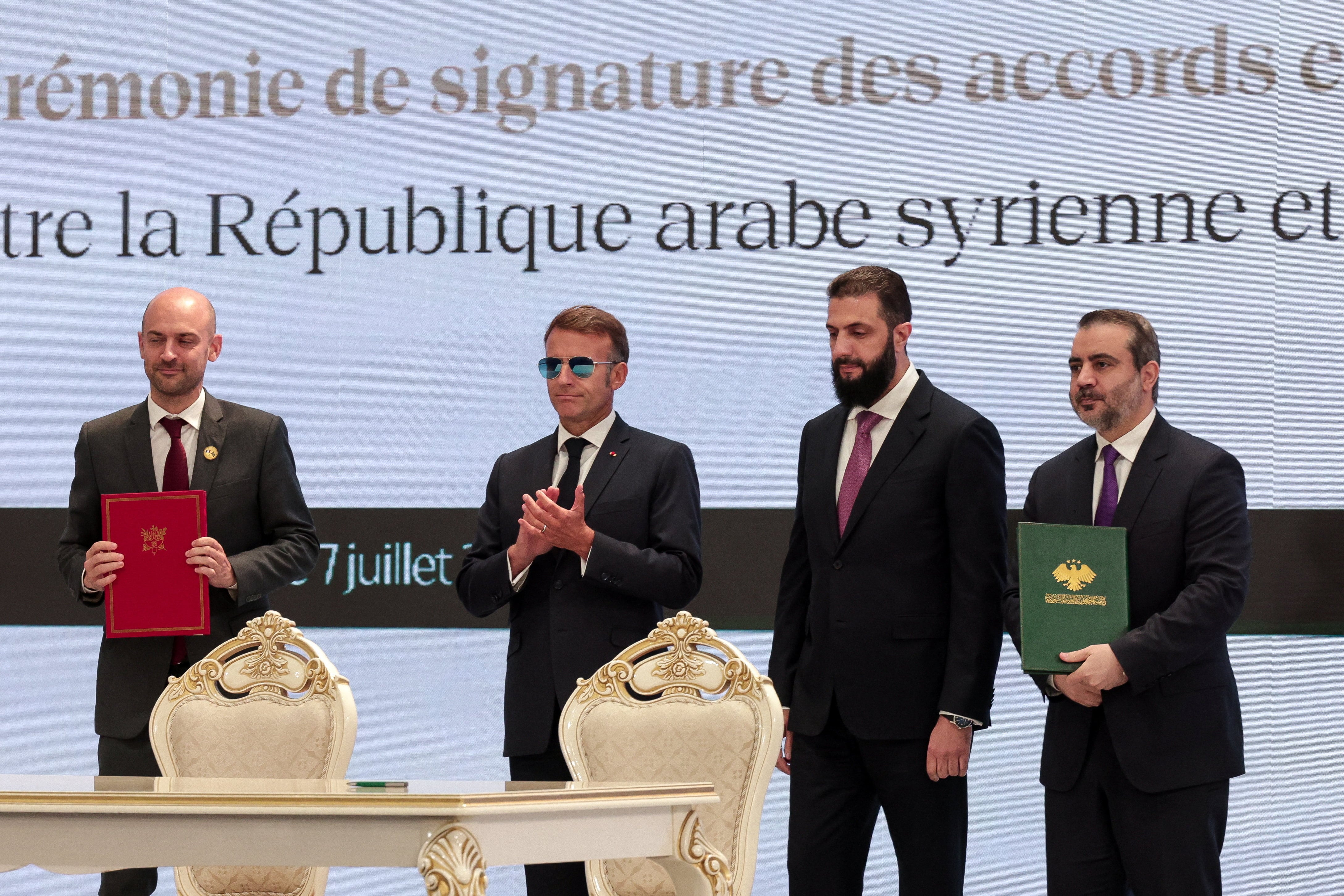Syria's Foreign Minister Asaad Hassan Al-Shaibani and France's Foreign Minister Jean-Noel Barrot hold documents next to France's President Emmanuel Macron and Syrian President Ahmed Al-Sharaa, at a signing ceremony in Damascus, Syria, July 7, 2026. REUTERS/Mahmoud Hassano