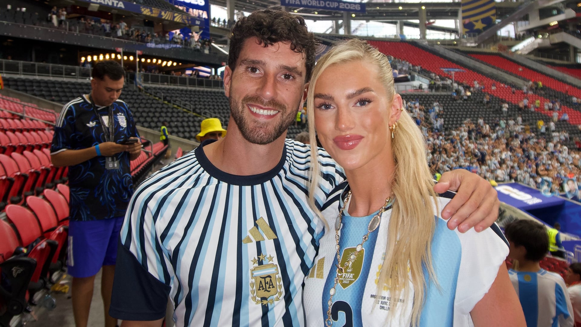 Marcos Senesi y Kelci-Rose Bowers posan sonrientes en el Mercedes-Benz Stadium de Atlanta, durante un evento relacionado con la Copa Mundial de la FIFA 2026.
