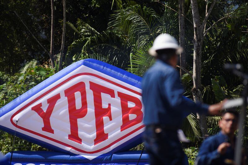 El logo de Yacimientos Petrolíferos Fiscales Bolivianos (YPFB) detrás de un trabajador en un campo petrolero en Bolivia. 16 de julio de 2024 (REUTERS/Claudia Morales)