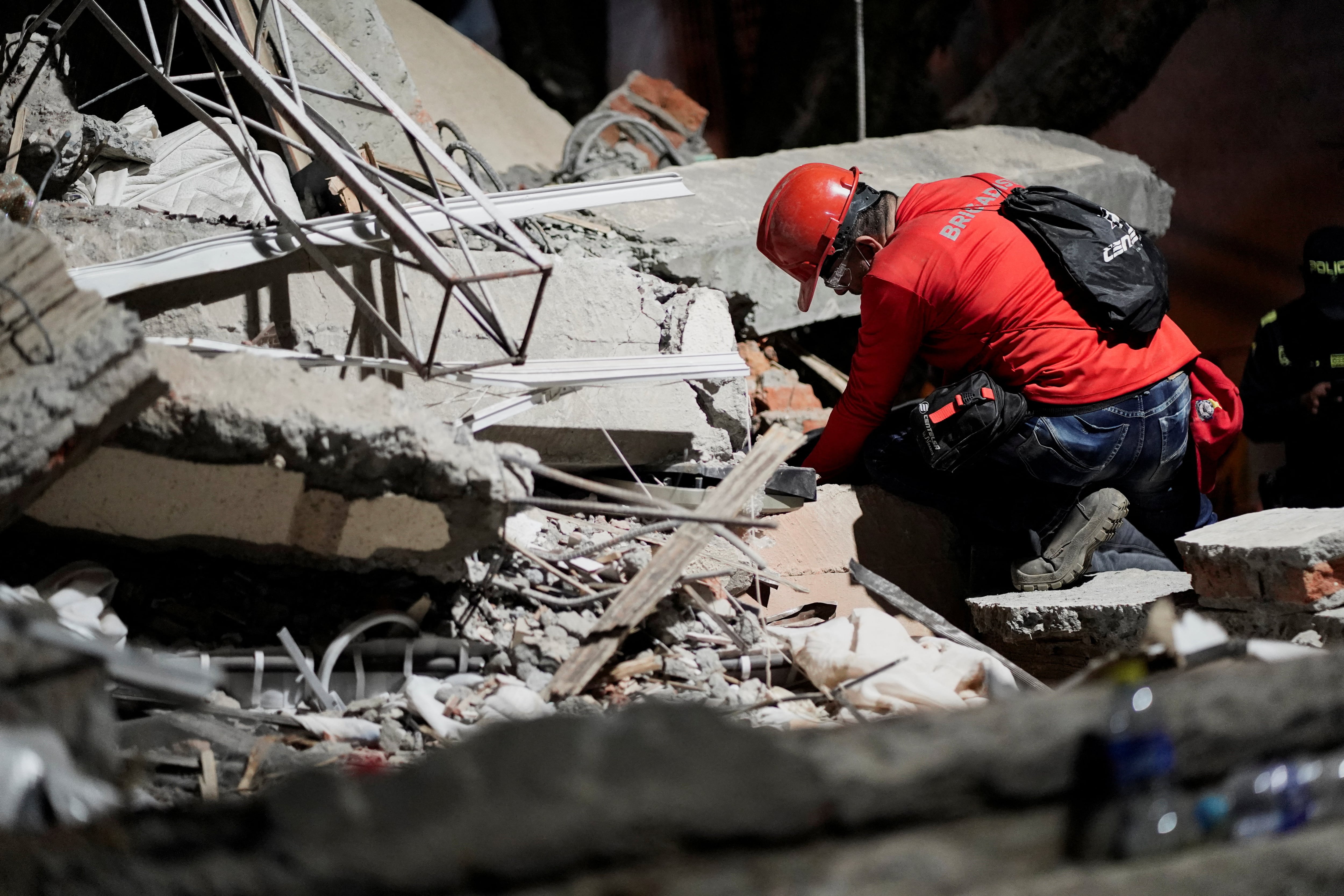 A rescuer searches for survivors under the rubble at the Torres de Limonar building in the aftermath of an earthquake, in Cali, Colombia, August 11, 2026. REUTERS/Sergio Acero