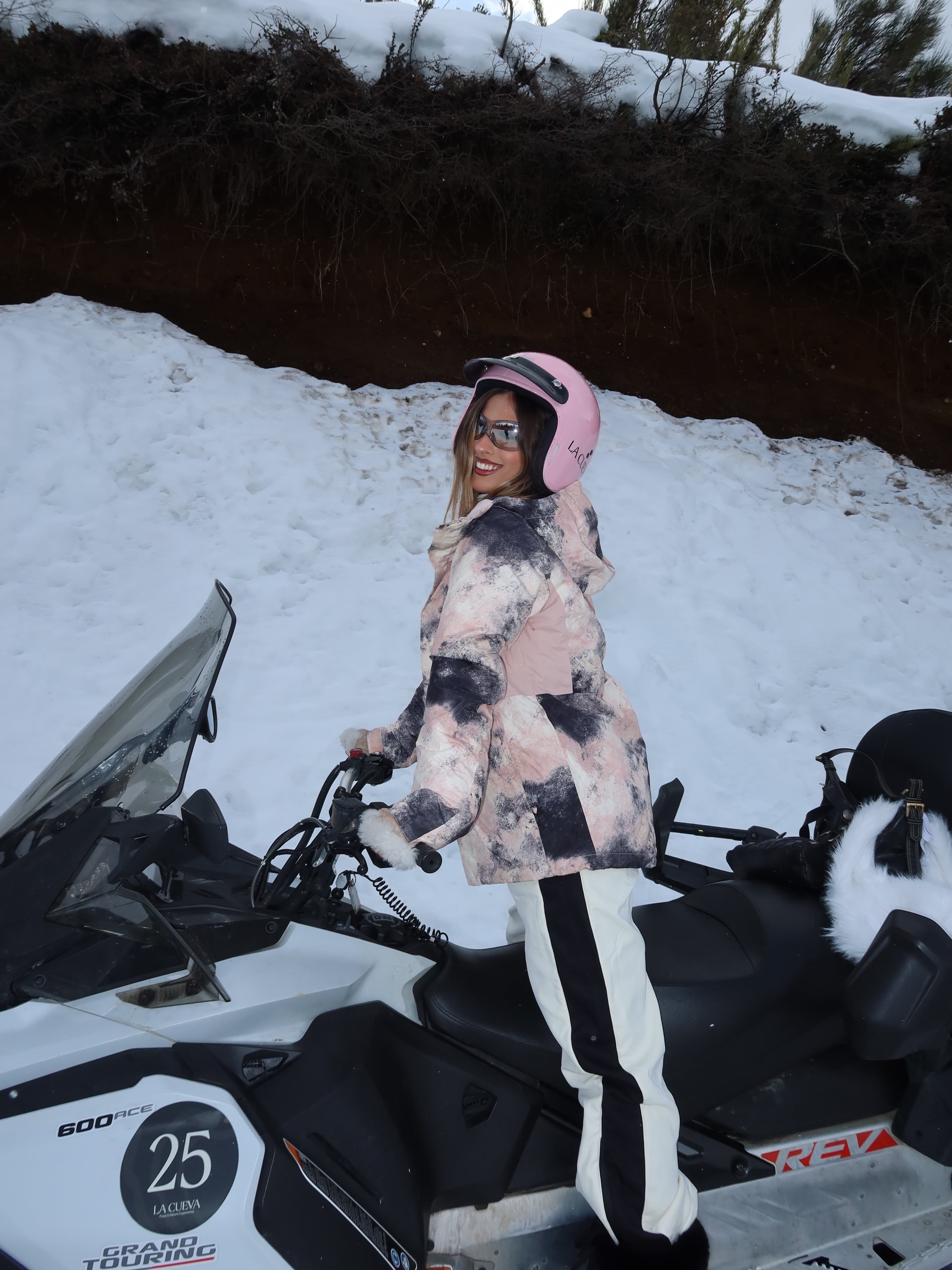 Poggio manejó una moto de nieve con casco rosa y campera en tonos rosados y grises durante el recorrido por los cerros