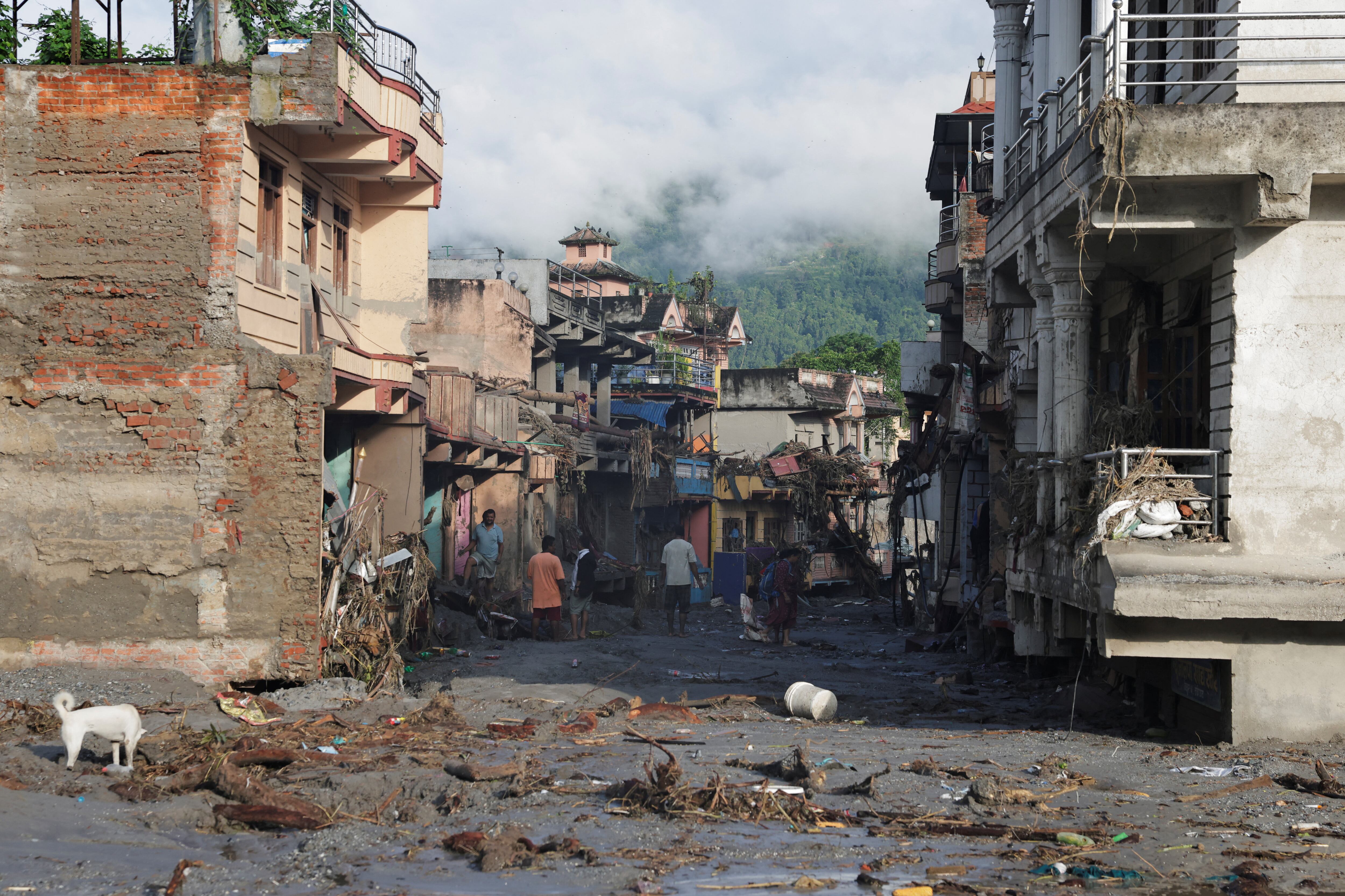 Personas permanecen junto a sus propiedades dañadas tras unas inundaciones repentinas y un deslizamiento de tierra en Trishuli, distrito de Nuwakot, Nepal, el 28 de agosto de 2026 (REUTERS/Navesh Chitrakar)