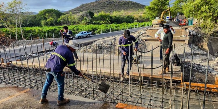 Un grupo de obreros prepara la estructura de varillas de acero para la cimentación de una obra junto a una carretera. (Agencia Guatemalteca de Noticias)