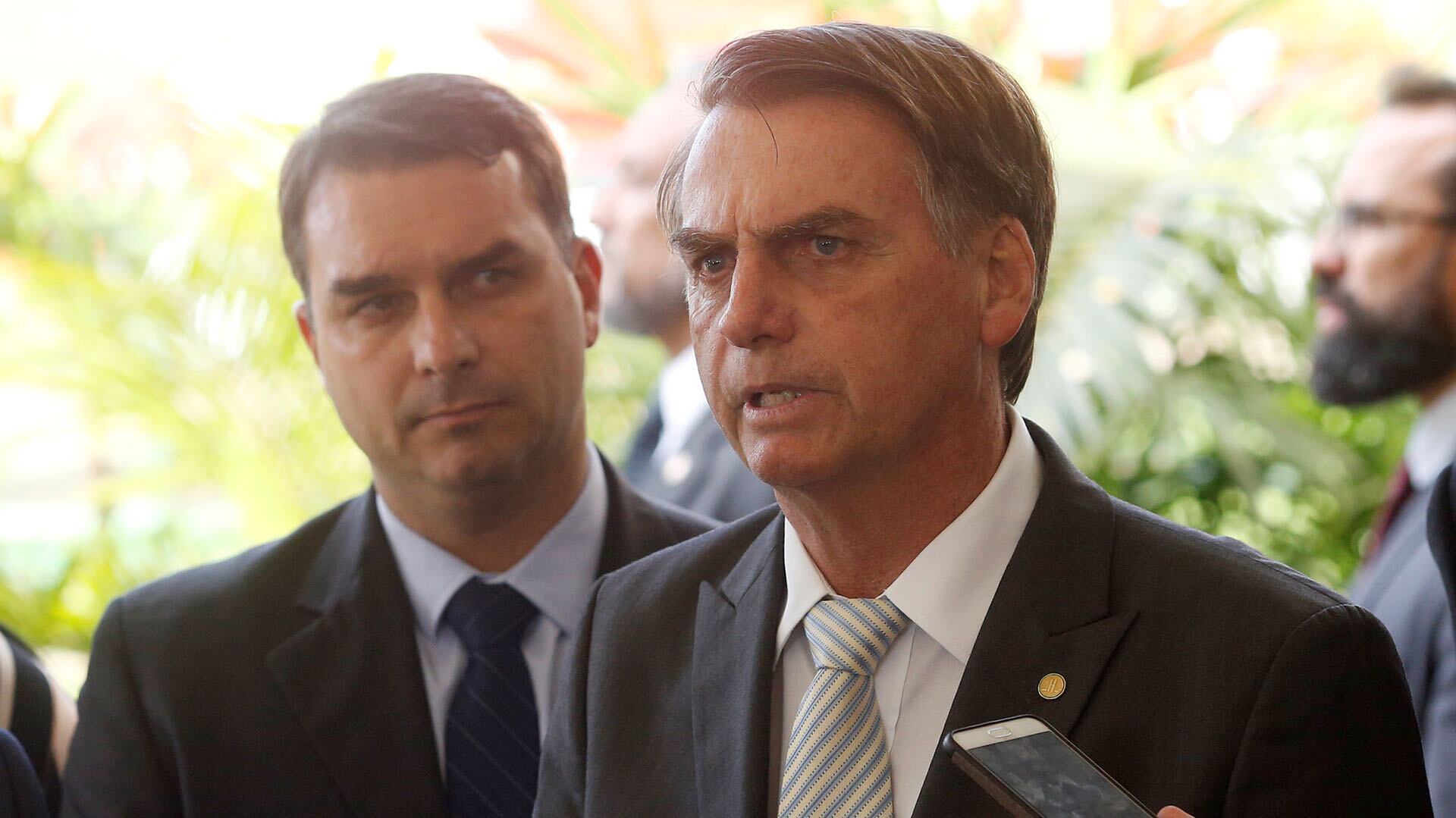Jair Bolsonaro habla a la prensa y detrás suyo está su hijo Flávio (ADRIANO MACHADO/REUTERS)