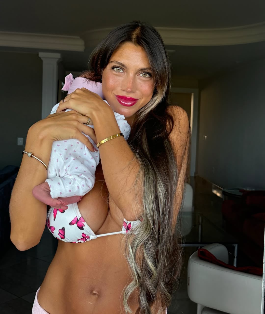 Cielo López, esposa del futbolista Claudio Spinelli, sostiene a su bebé en brazos.