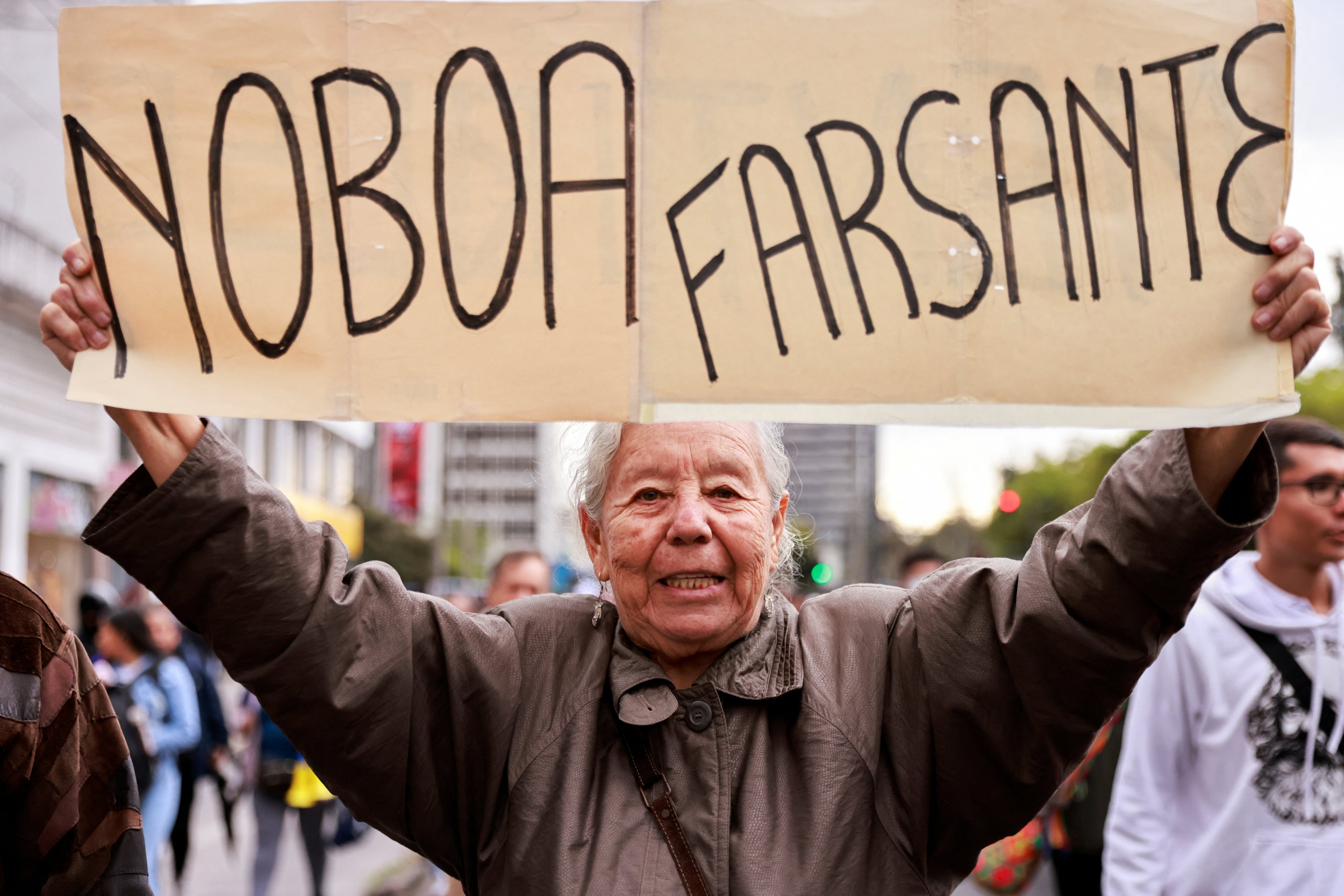 Una mujer mayor sostiene un cartel que dice 