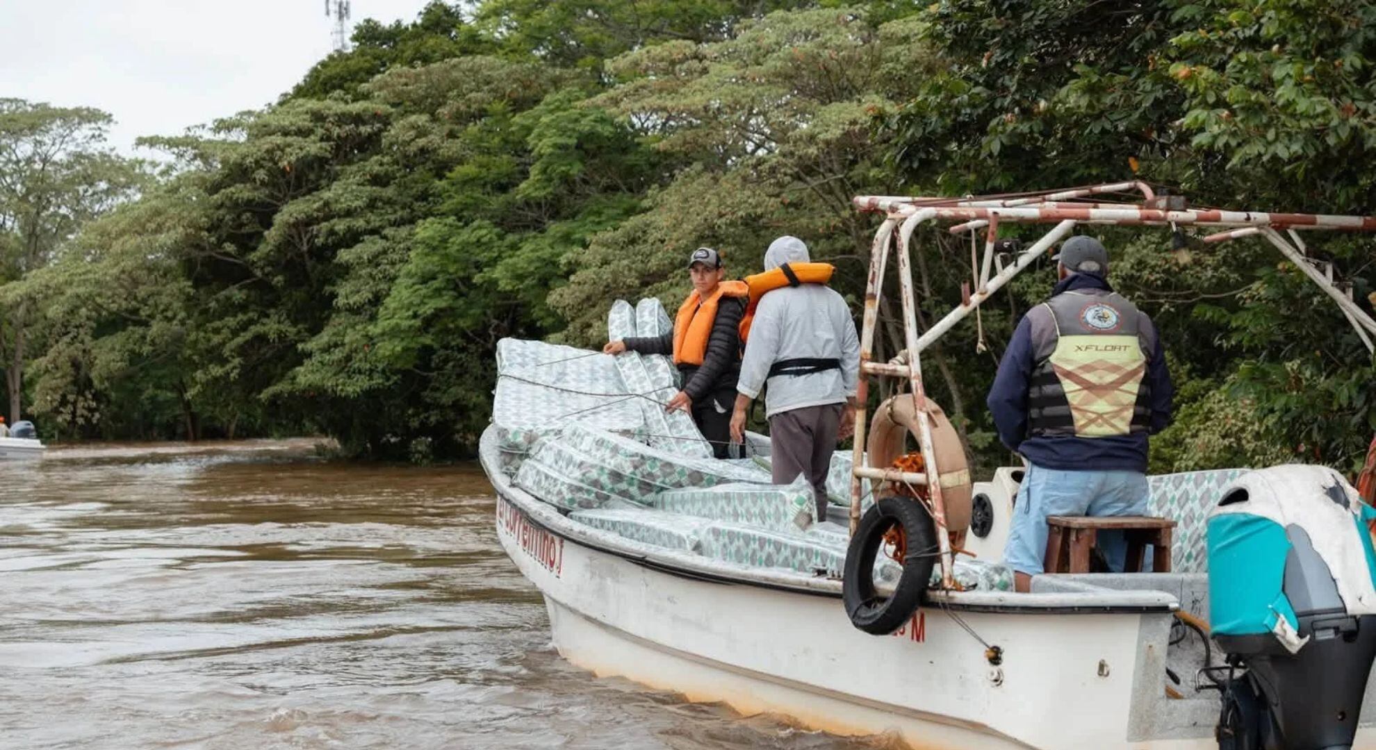 Una embarcación traslada colchones protegidos con plástico y a tripulantes con chalecos salvavidas por las aguas cercanas a la Isla Apipé.