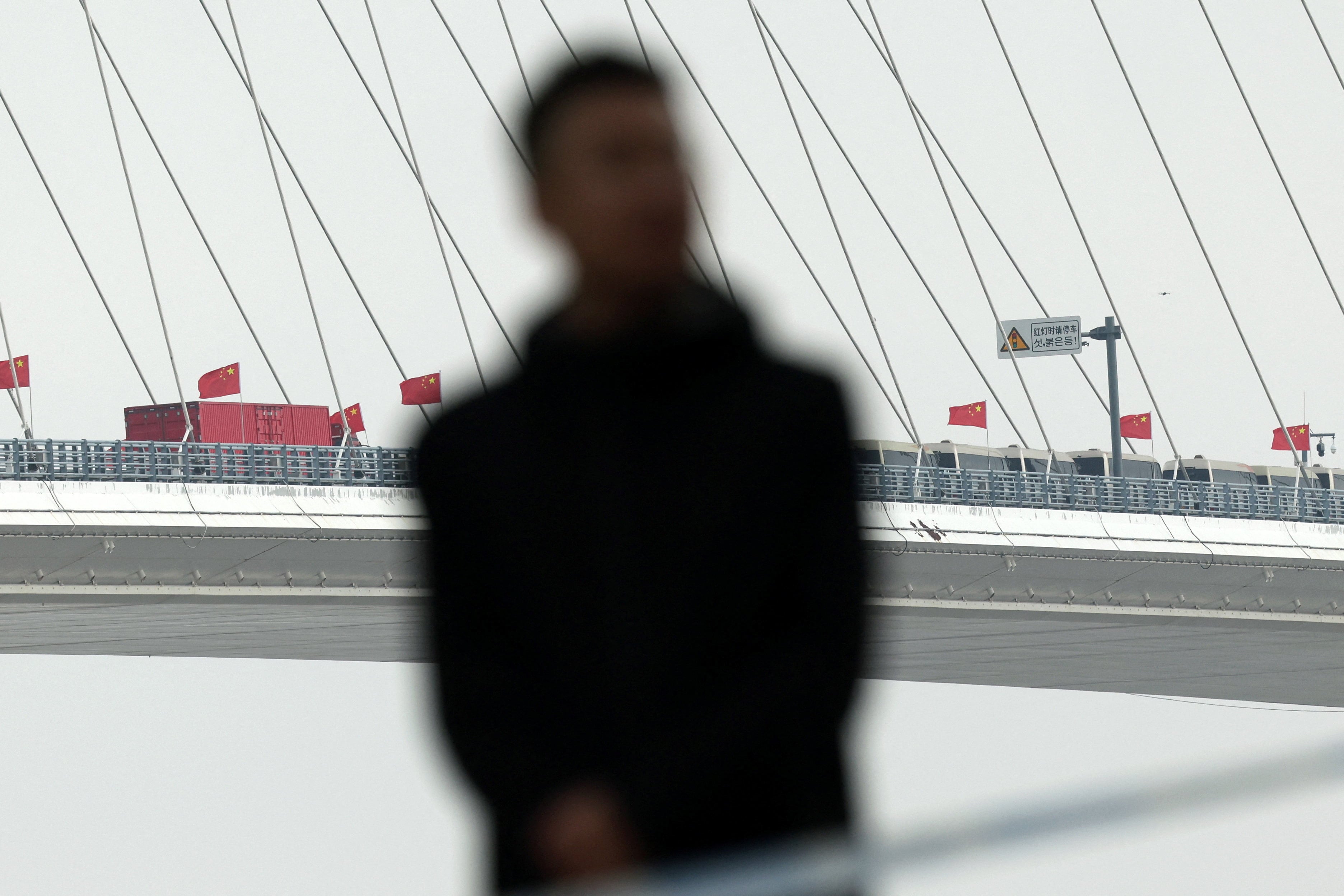 Un miembro del personal de seguridad vigila una zona ribereña acordonada durante la ceremonia de inauguración del Nuevo Puente del Río Yalu, el 15 de octubre de 2026 (REUTERS/Florence Lo)